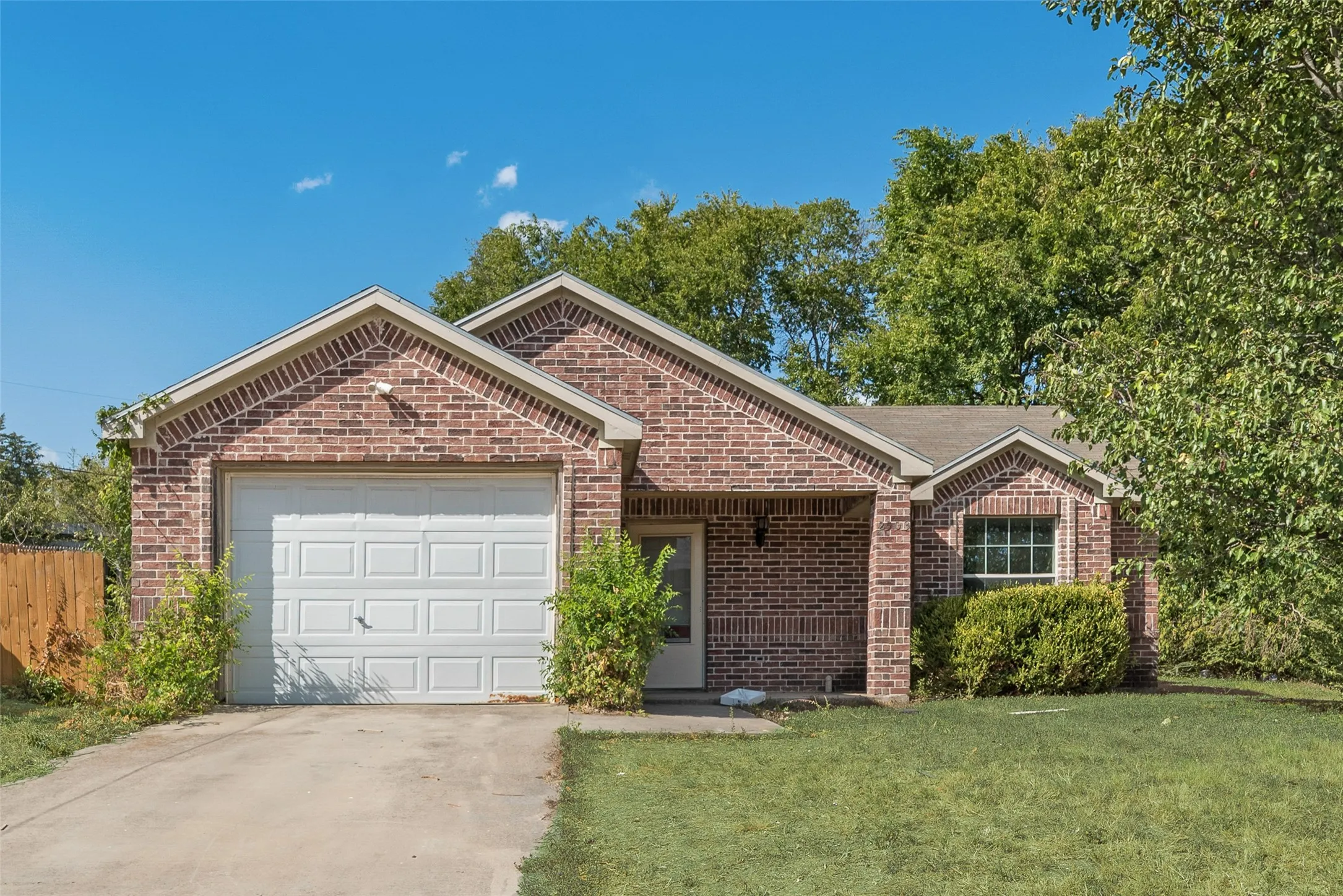 Brick facade, attached garage, gabled roofline, front entry, landscaped shrubs