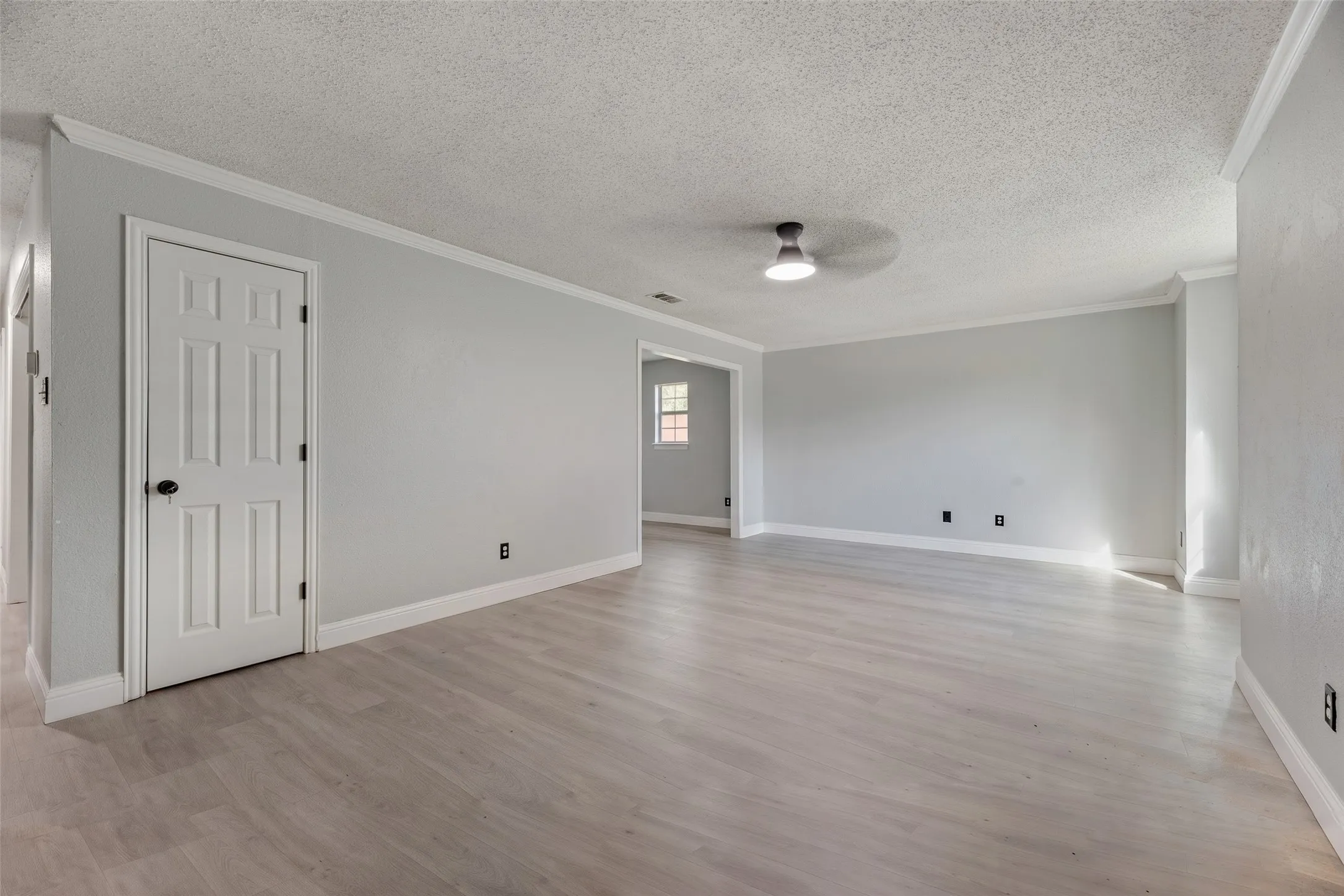 Spacious room with light gray walls, wood-finish flooring, white trim, and a contemporary ceiling fixture