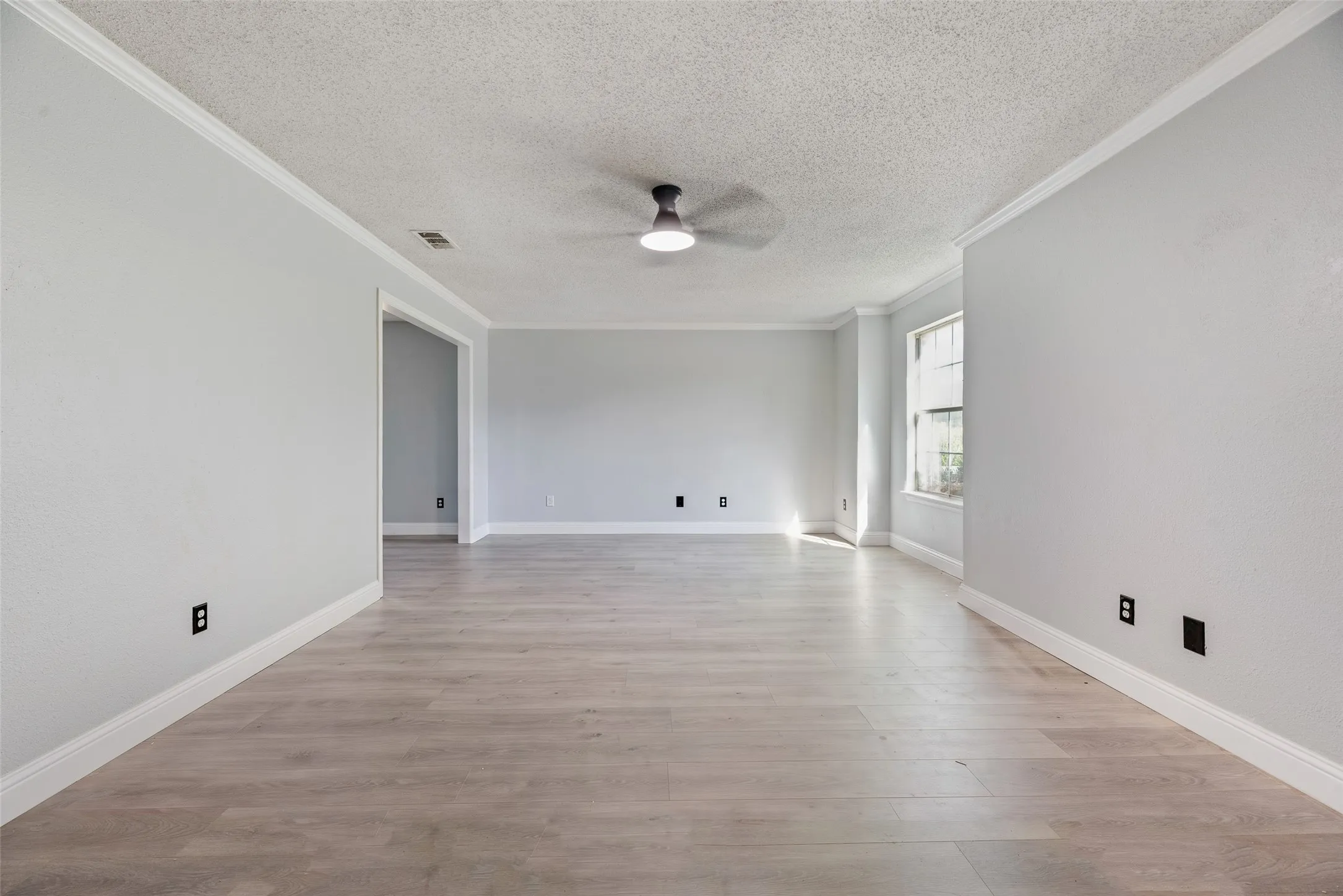 Wood-finish flooring, crown molding, modern ceiling fan, and white trim
