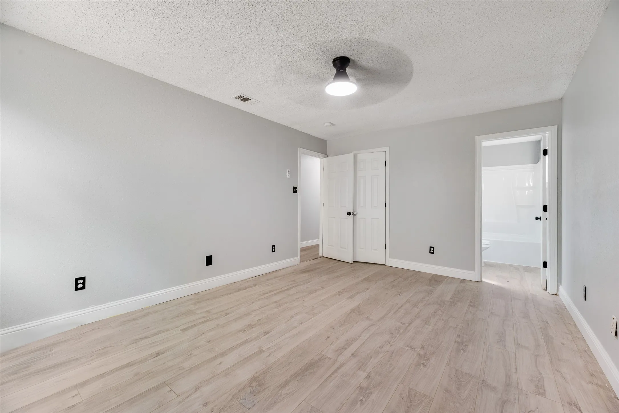 Wood-finish flooring, light gray wall paint, white trim, and a ceiling-mounted light fixture