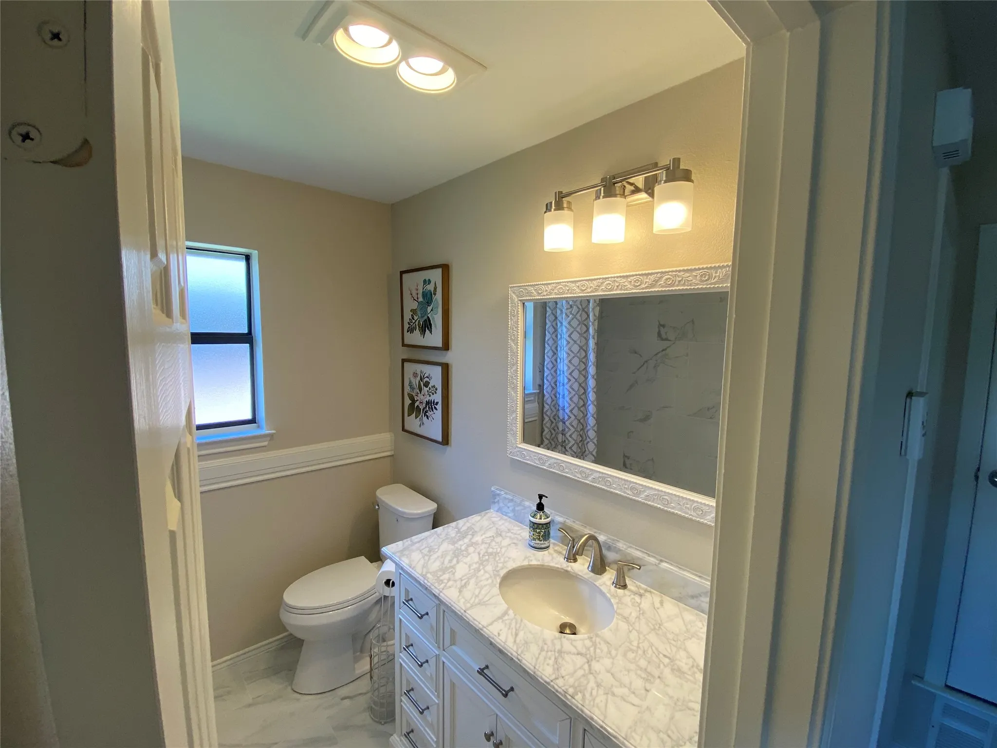 Vanity with a marble-finish countertop, undermount sink, and brushed nickel faucet