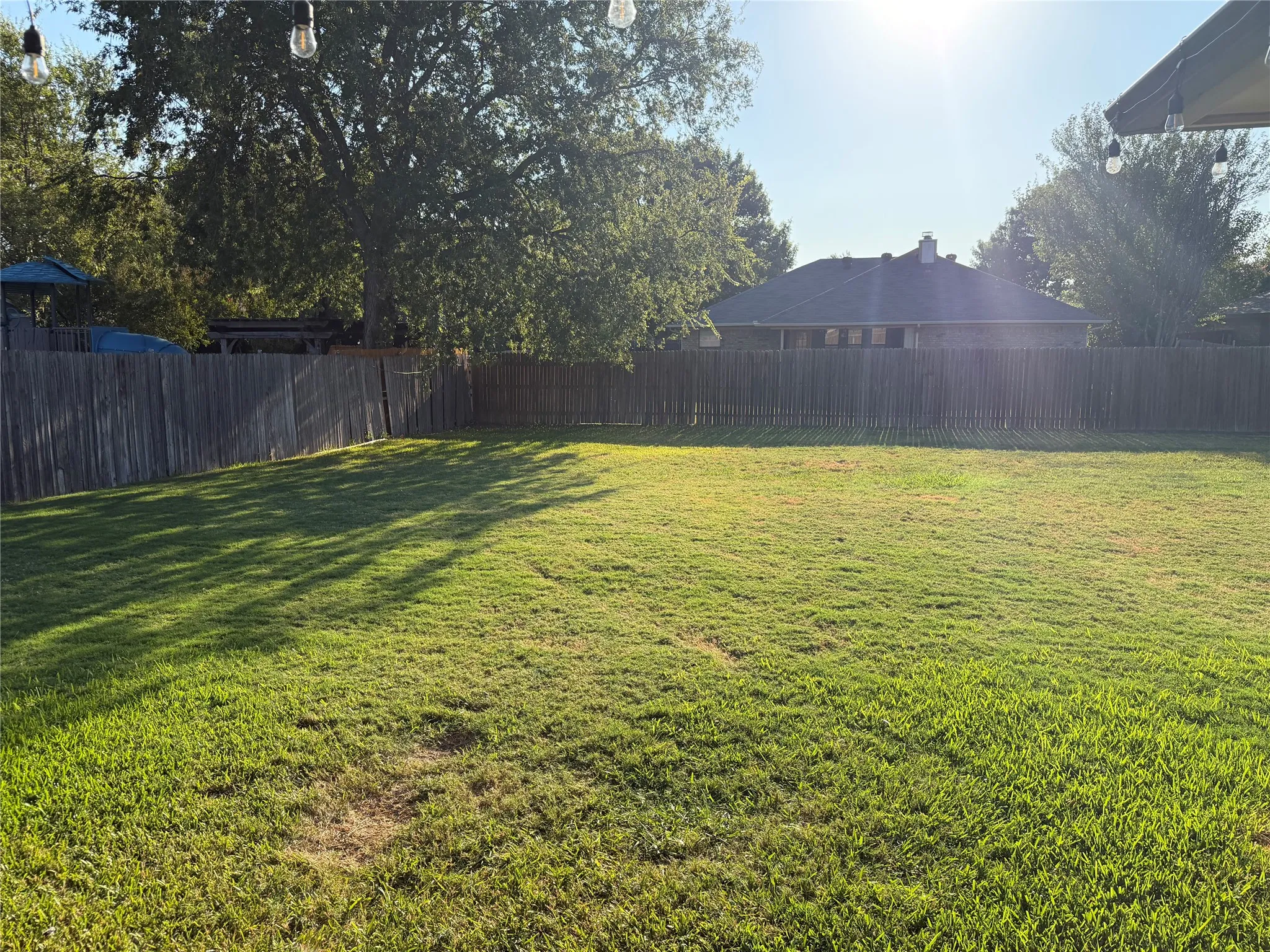 Expansive green lawn (backyard) with a full privacy fence
