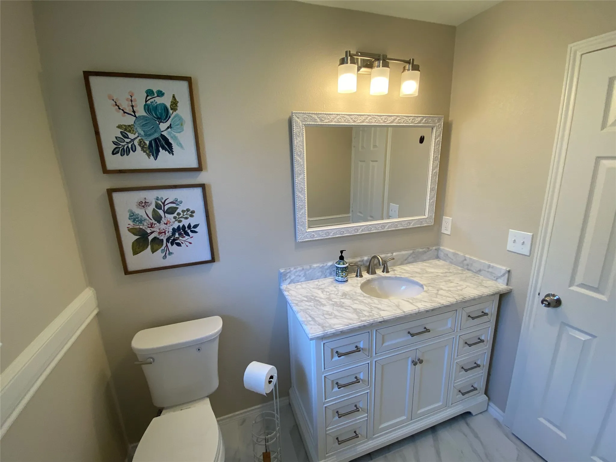 Vanity with a marble-finish countertop, single basin sink, and brushed nickel faucet