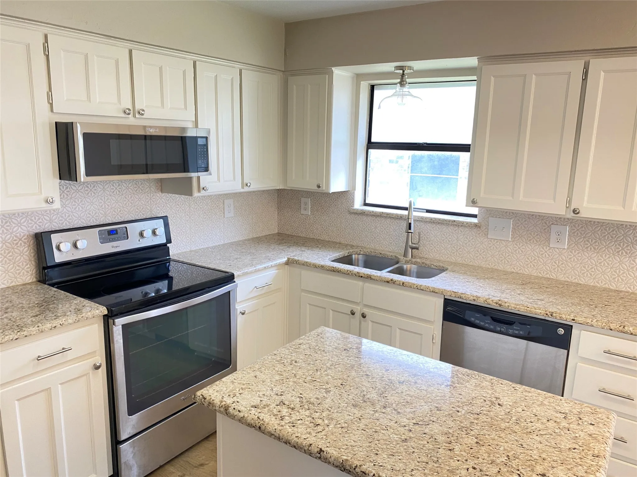 Kitchen featuring white cabinetry, granite countertops, stainless steel appliances, a double basin sink, and a tiled backsplash