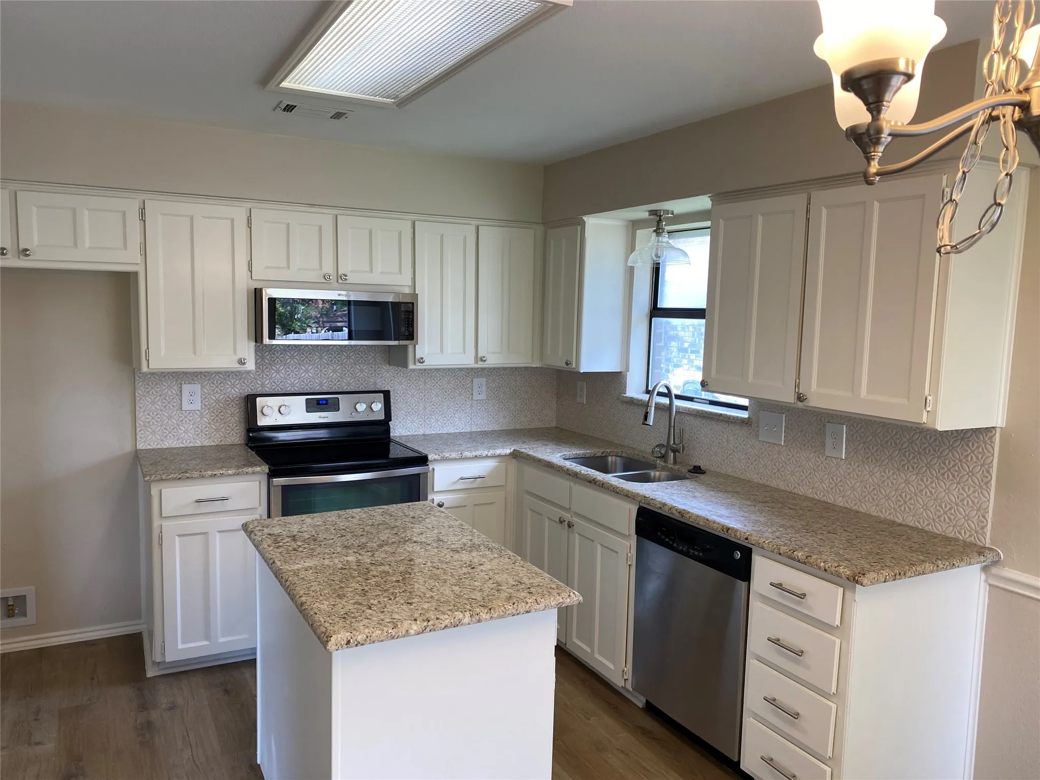 Kitchen featuring white cabinetry, granite countertops, stainless steel appliances, a tile backsplash, and wood-finish flooring