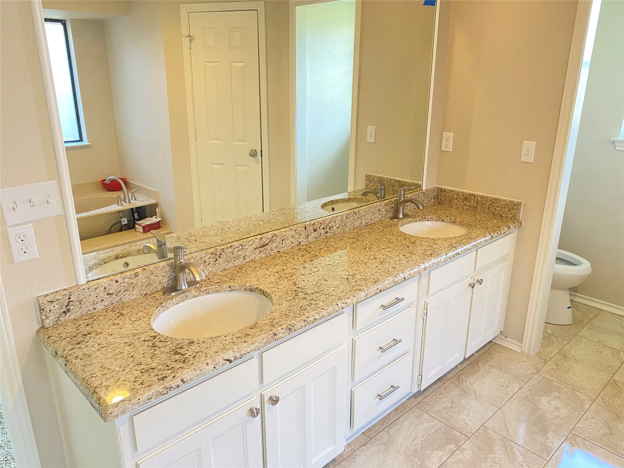 Dual vanity with granite countertops, undermount sinks, and white cabinetry