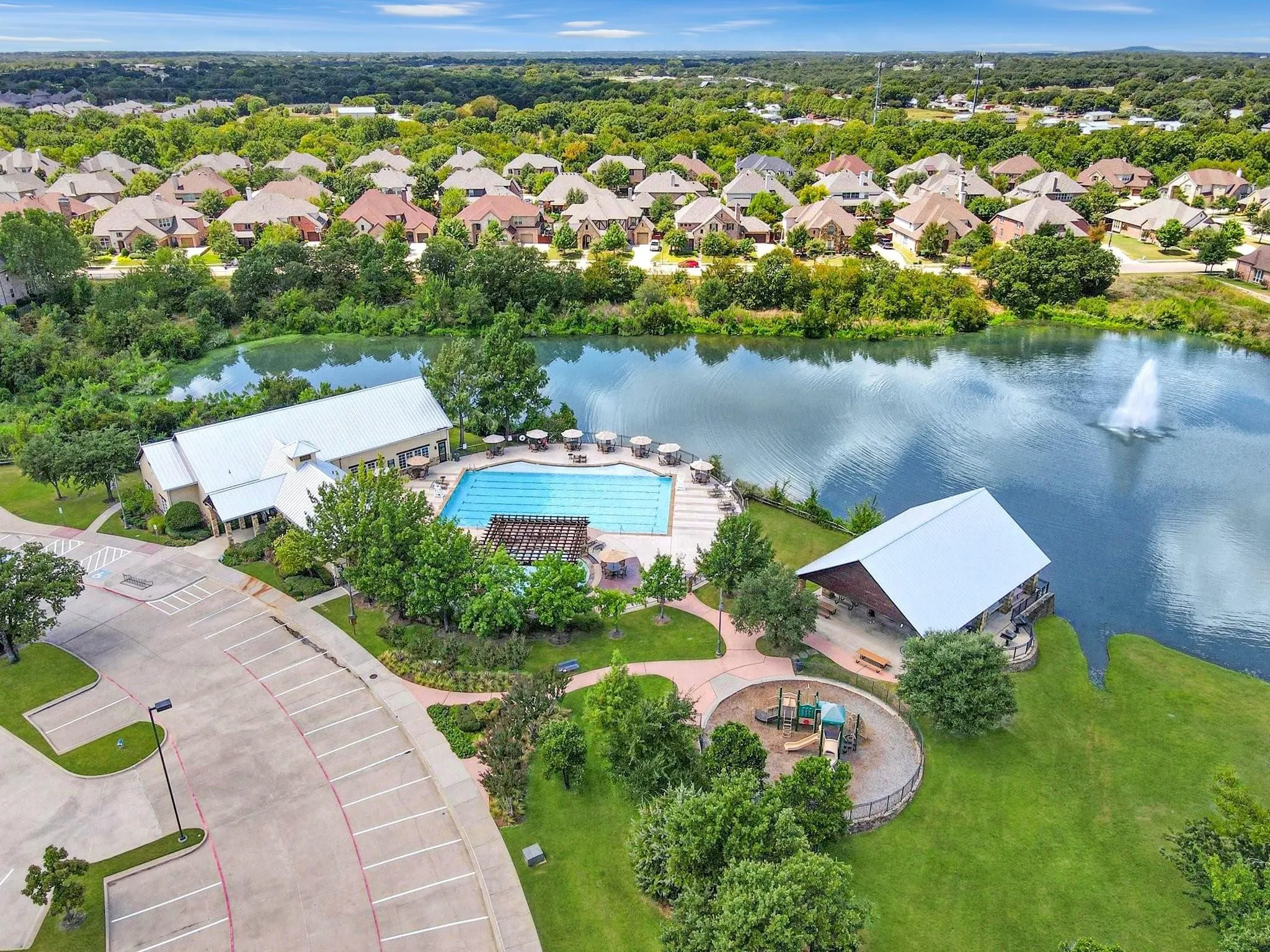 Community recreation center with a swimming pool, adjacent lake with a fountain, and a dedicated playground area