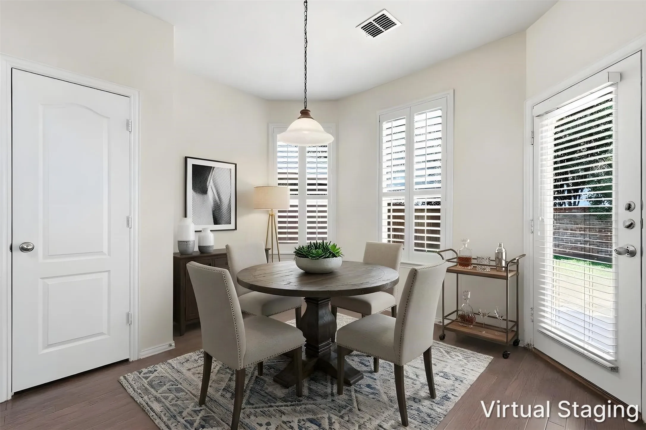 Recessed dining nook with wood-finish flooring, multiple windows with plantation shutters, and a pendant light fixture