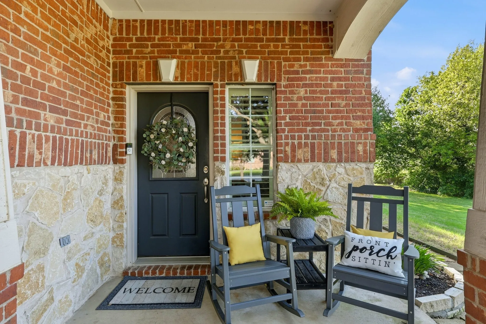 Brick and stone facade with an arched entry door and a covered porch