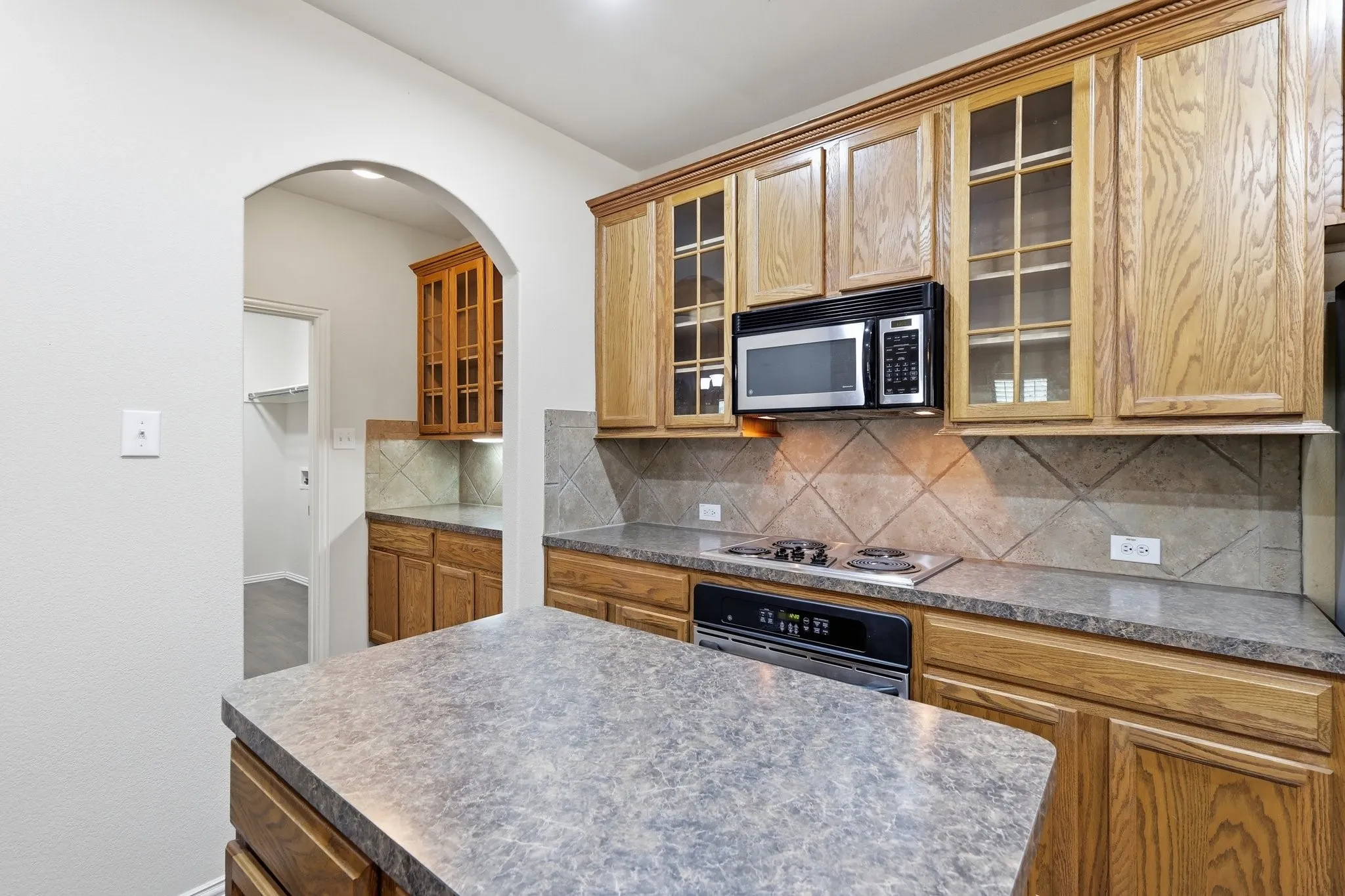 Kitchen featuring wood cabinetry, stone-look countertops, and a built-in microwave