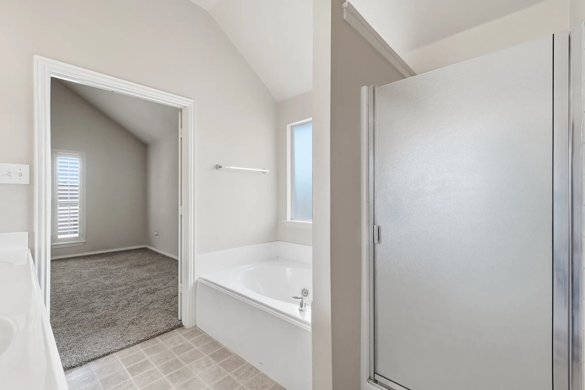 Built-in soaking tub, separate shower with frosted glass enclosure, and a frosted window