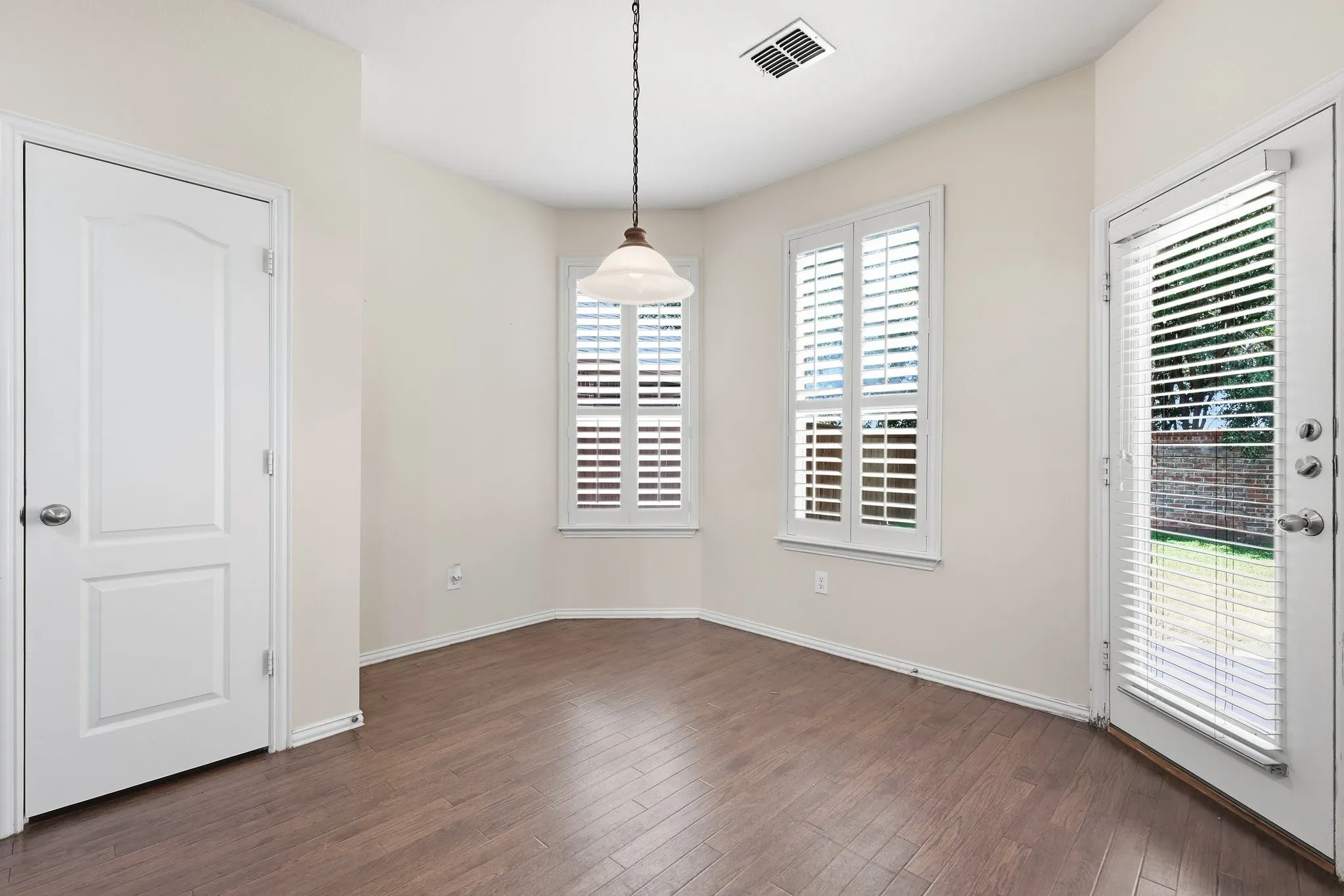 Wood-finish flooring, white plantation shutters, white paneled doors, and a ceiling-mounted light fixture