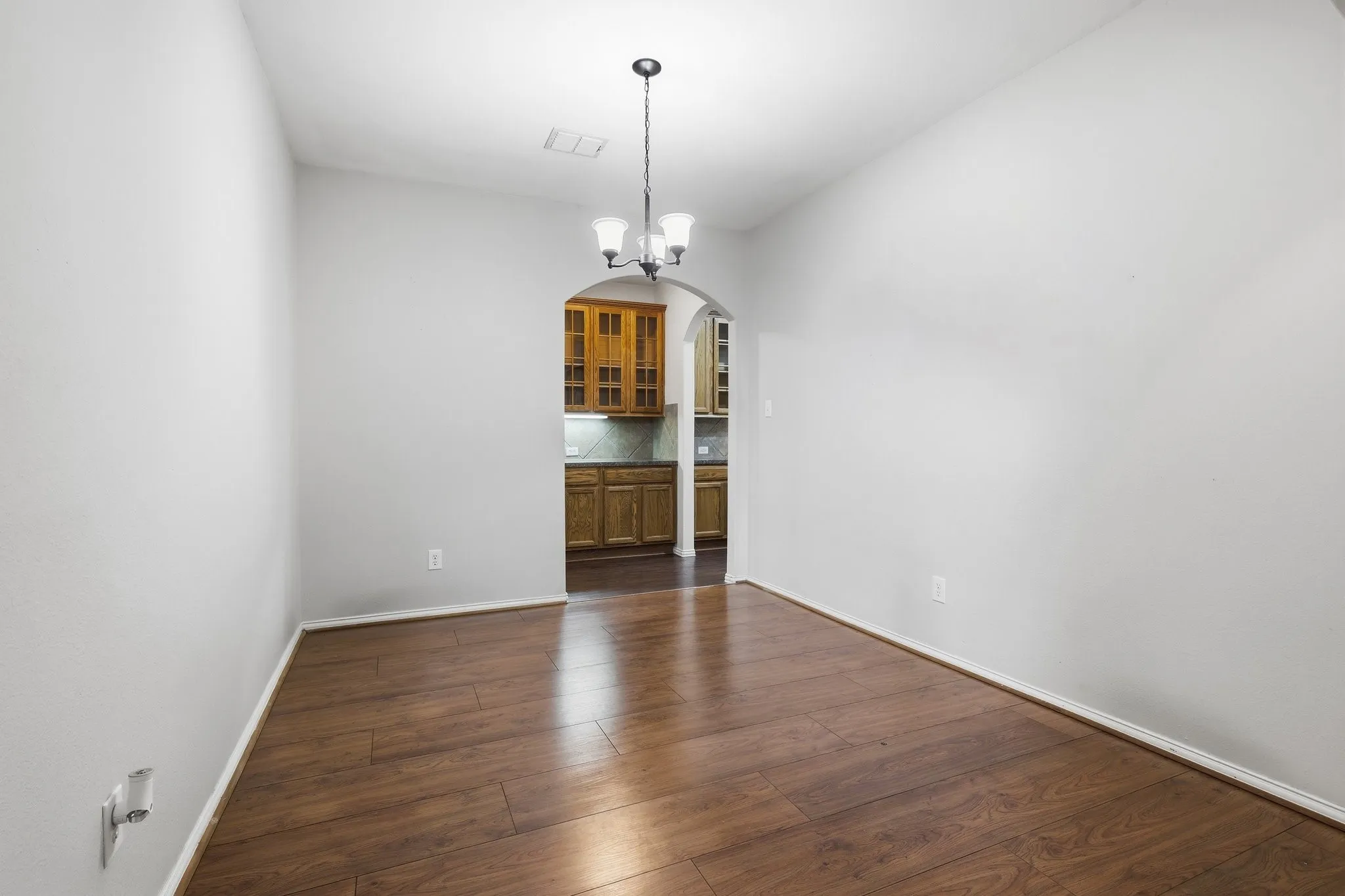 Wood-finish flooring, pendant lighting, and an arched entryway