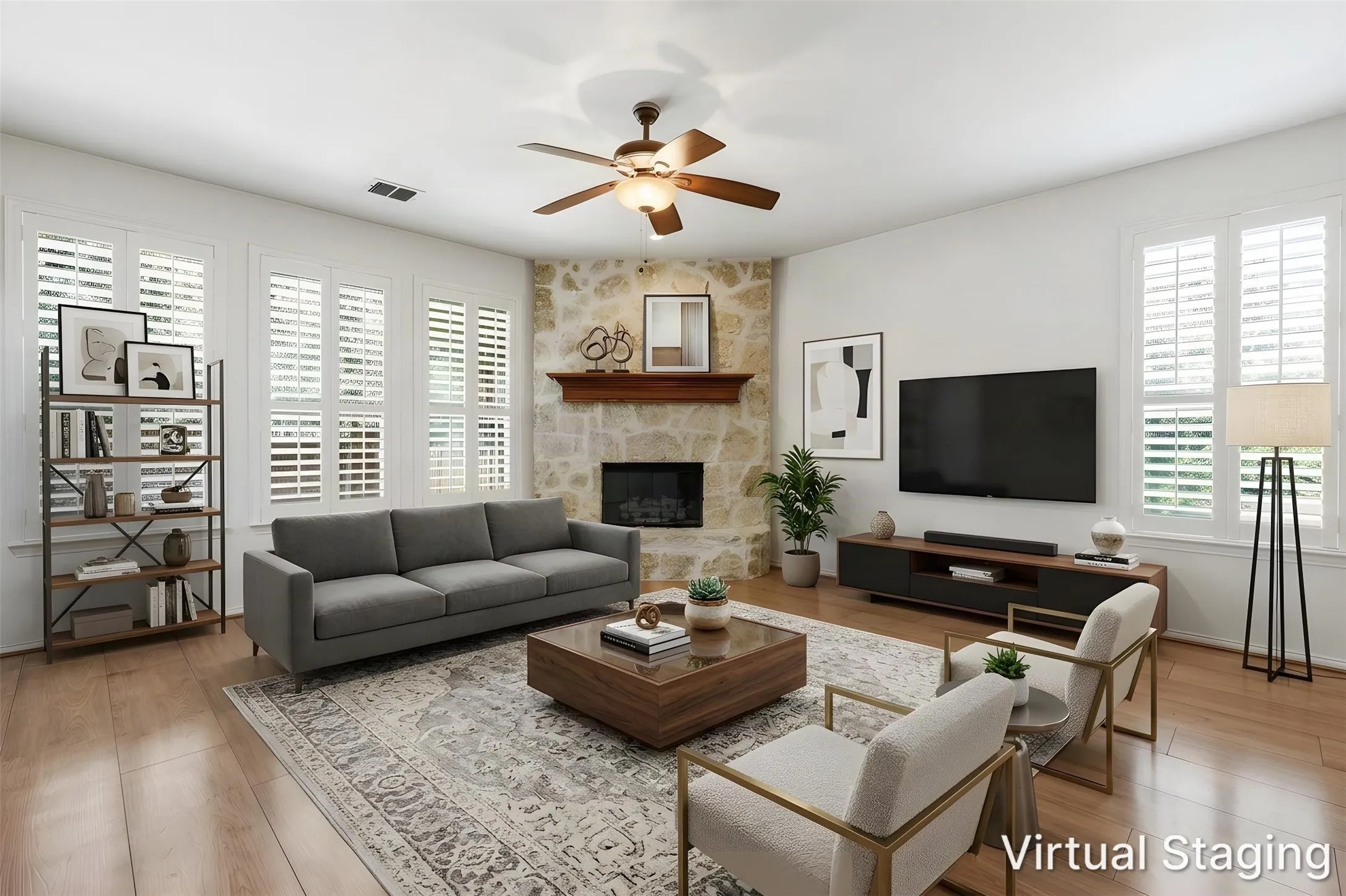 Corner stone fireplace with a wood mantel, multiple windows with plantation shutters, wood-finish flooring, and a ceiling fan