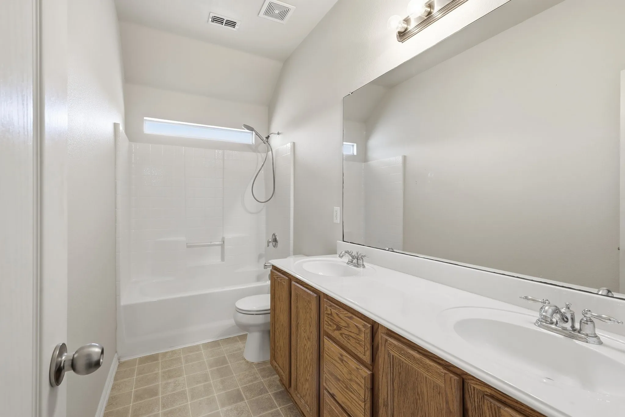 Bathroom featuring a dual vanity with wood-finish cabinetry, white countertops, and chrome fixtures