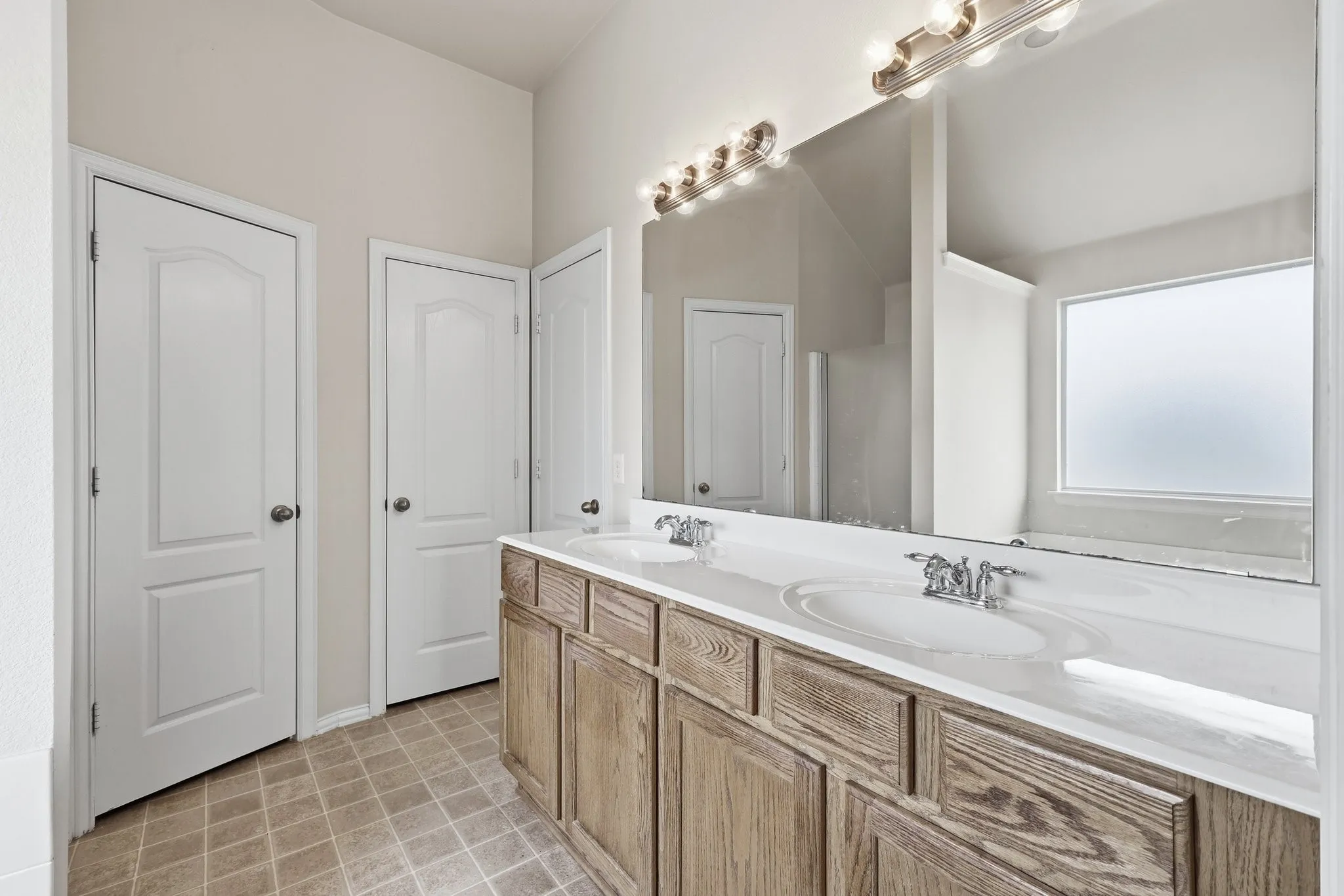 Double vanity with wood-finish cabinetry, dual sinks, and a large wall-mounted mirror