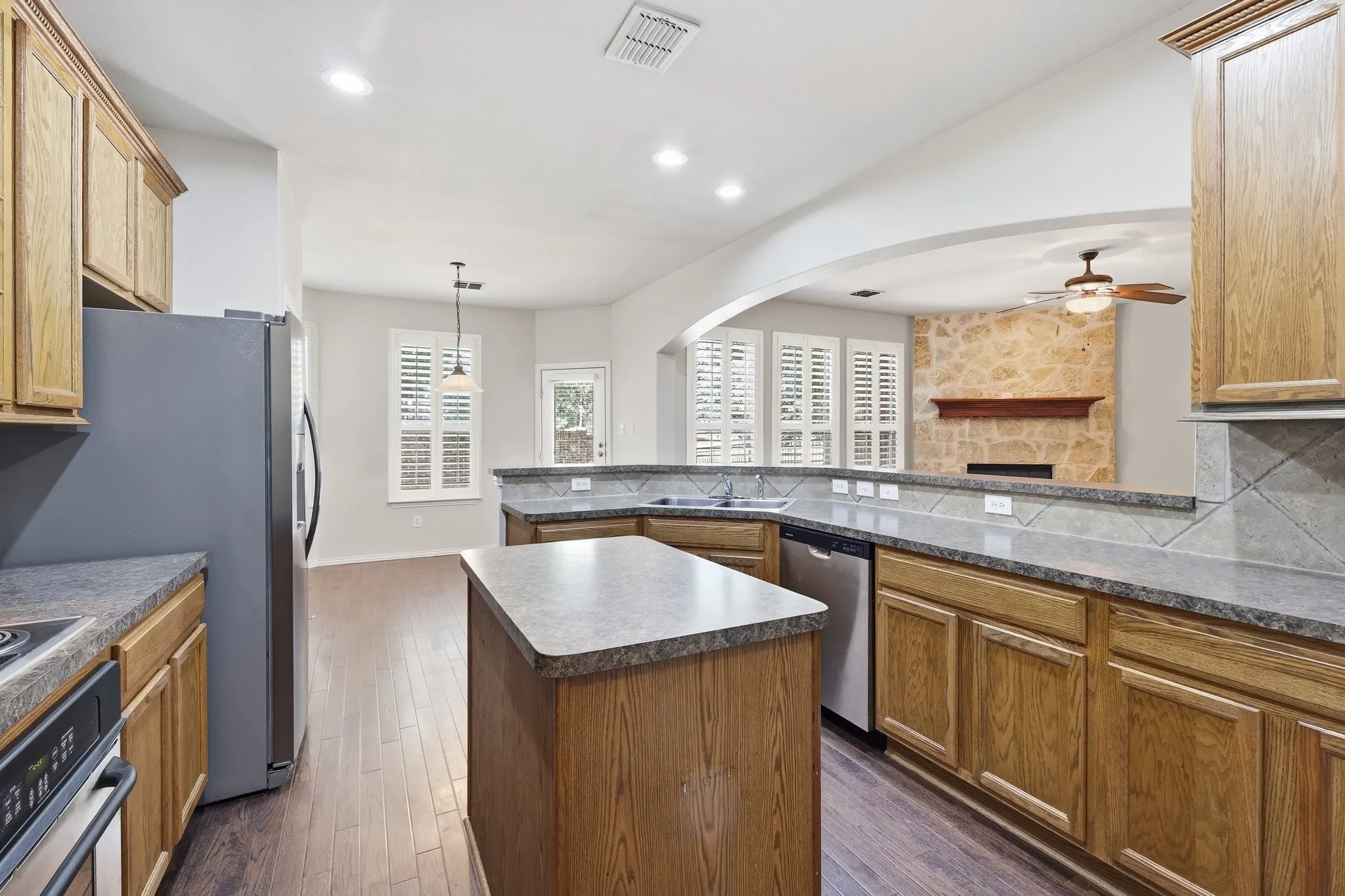 Kitchen featuring wood-finish cabinetry, stainless steel appliances, a center island, and wood-finish flooring