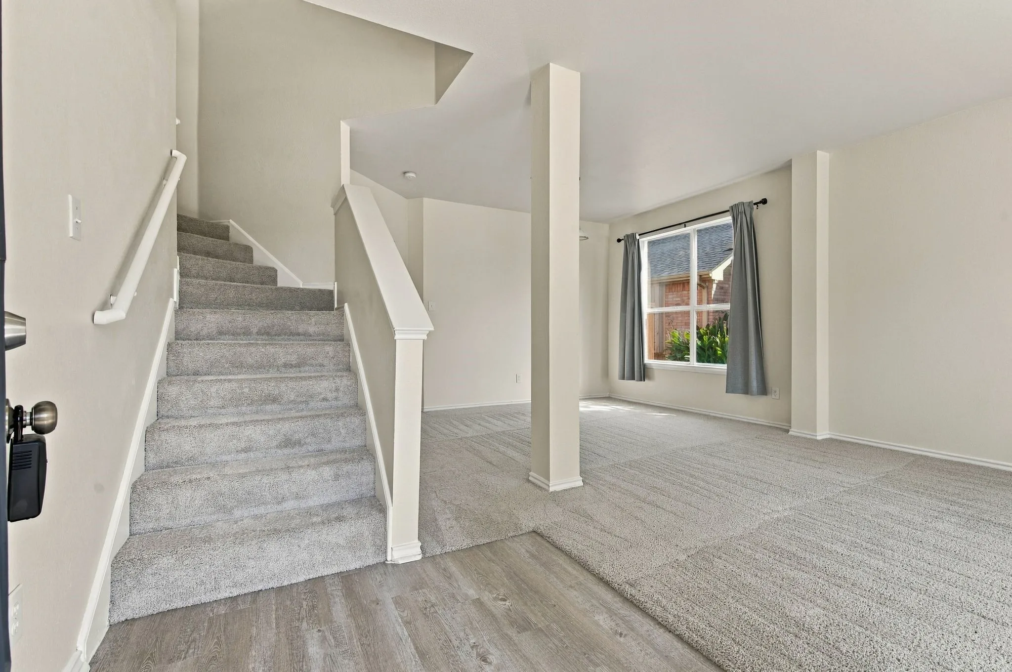 Carpeted staircase with white railings, wood-finish flooring, and a large window with white trim