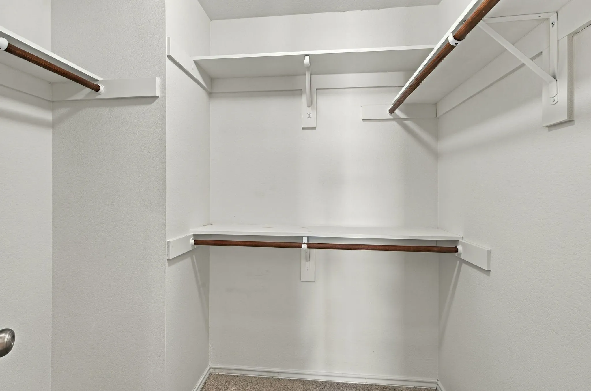 Built-in shelving with hanging rods and neutral-toned carpeting