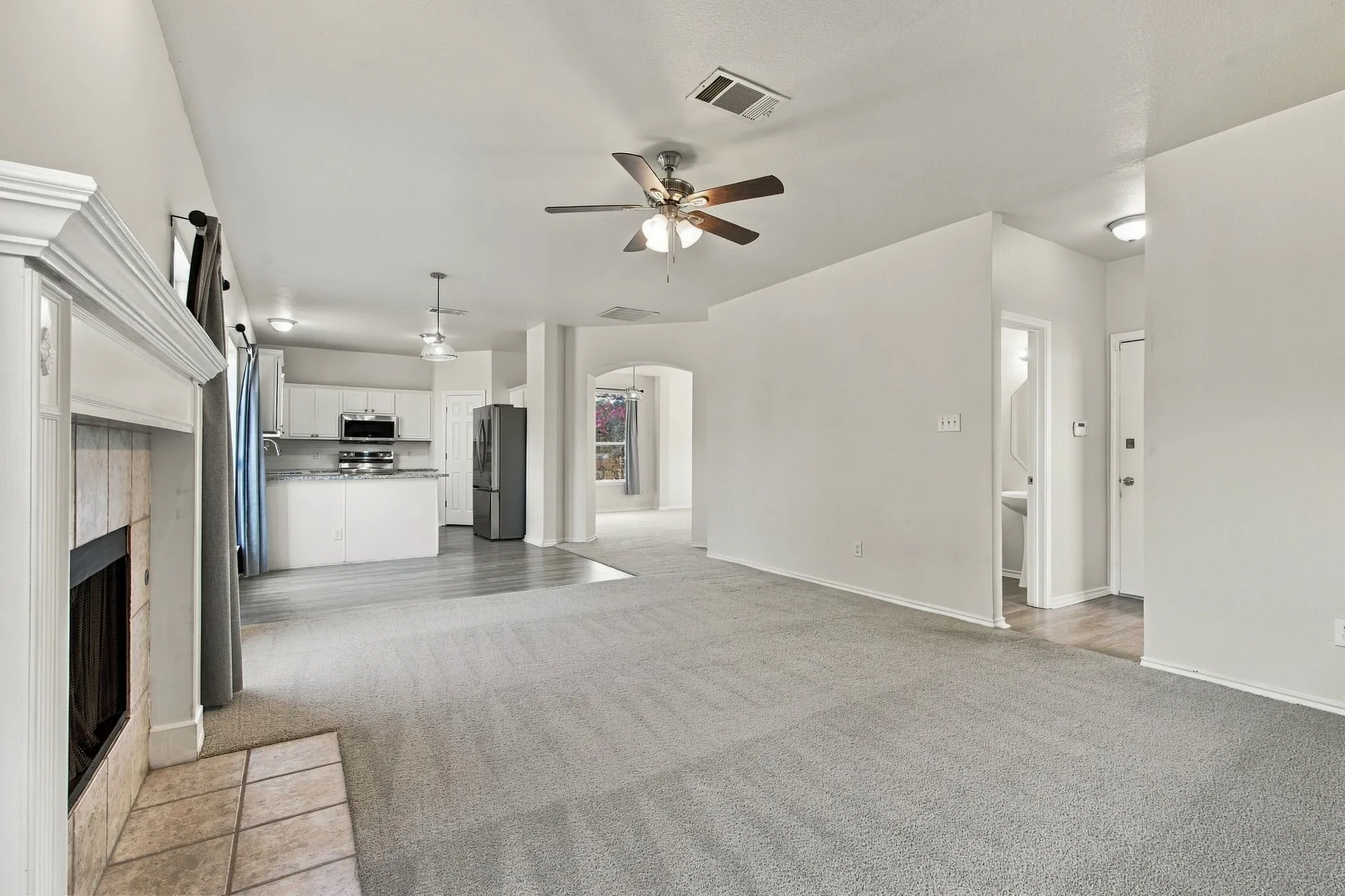Carpeted living area with a fireplace featuring a tile hearth and a decorative mantel