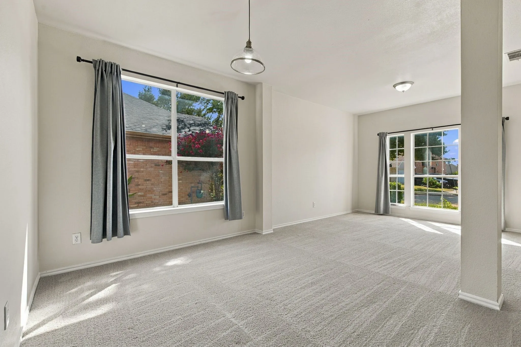Neutral-toned walls, light gray carpeting, and multiple windows with white trim