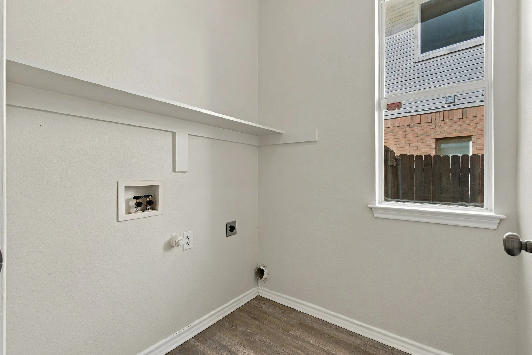Laundry area featuring wood-finish flooring, built-in shelving, and a white-framed window
