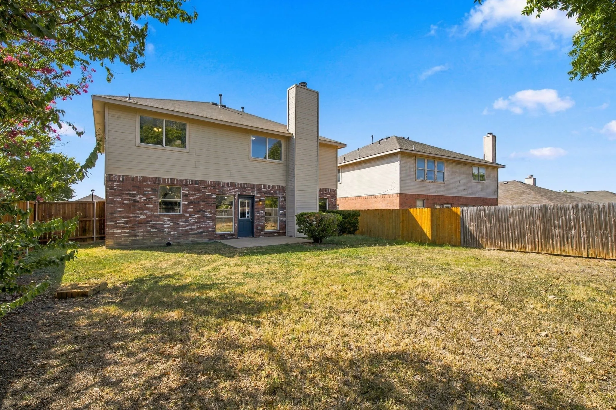 Expansive backyard with a manicured lawn, concrete patio, and full privacy fencing