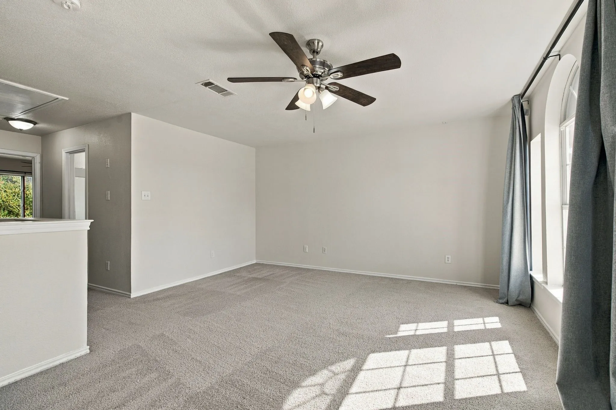 Recessed ceiling fan with light fixture, arched window, soft gray carpeting, and neutral wall tones