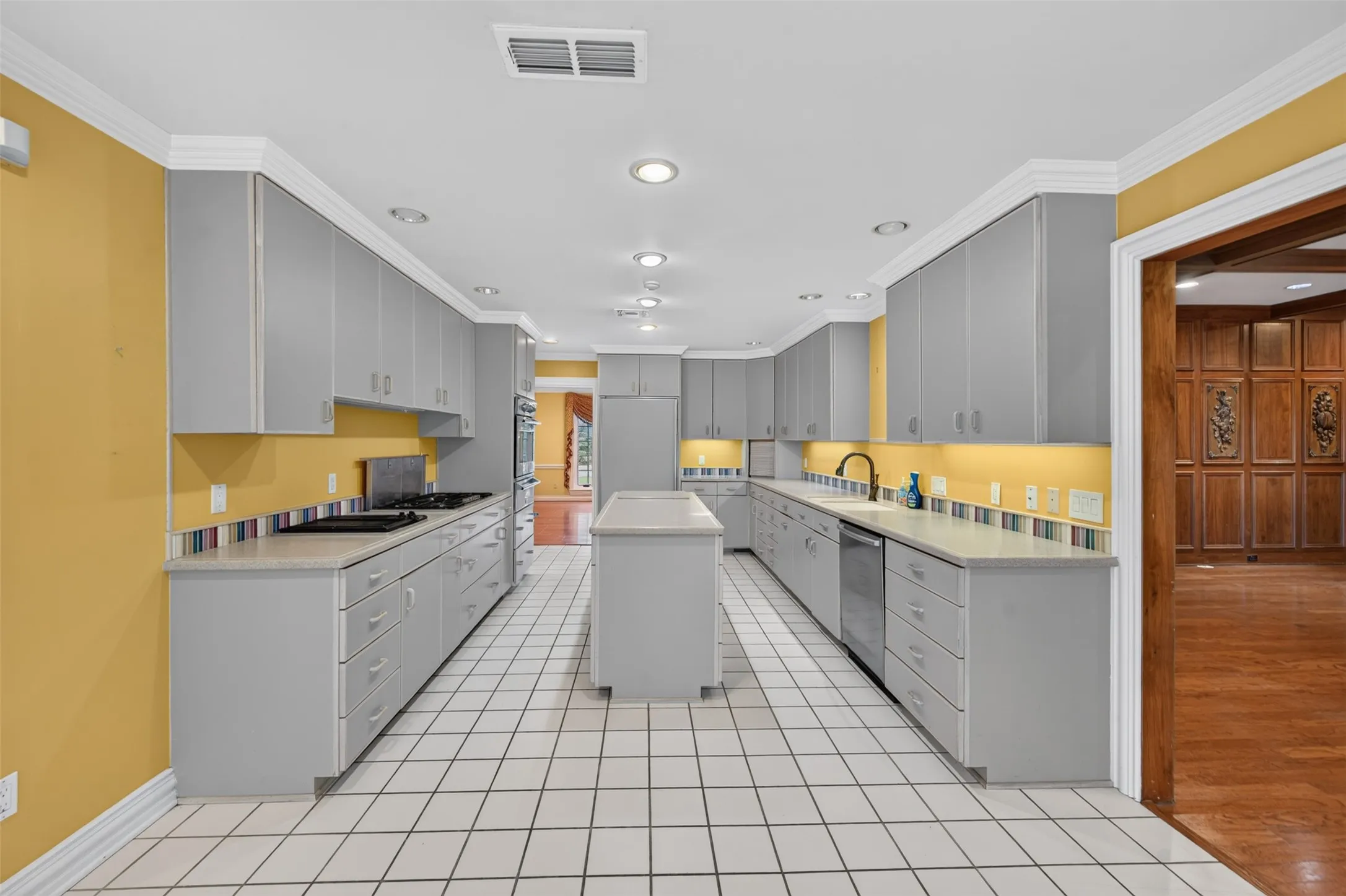 Galley kitchen featuring a gas range, integrated oven with two warming drawers, dishwasher, recessed lighting, a center island and a Sub-Zero refrigerator