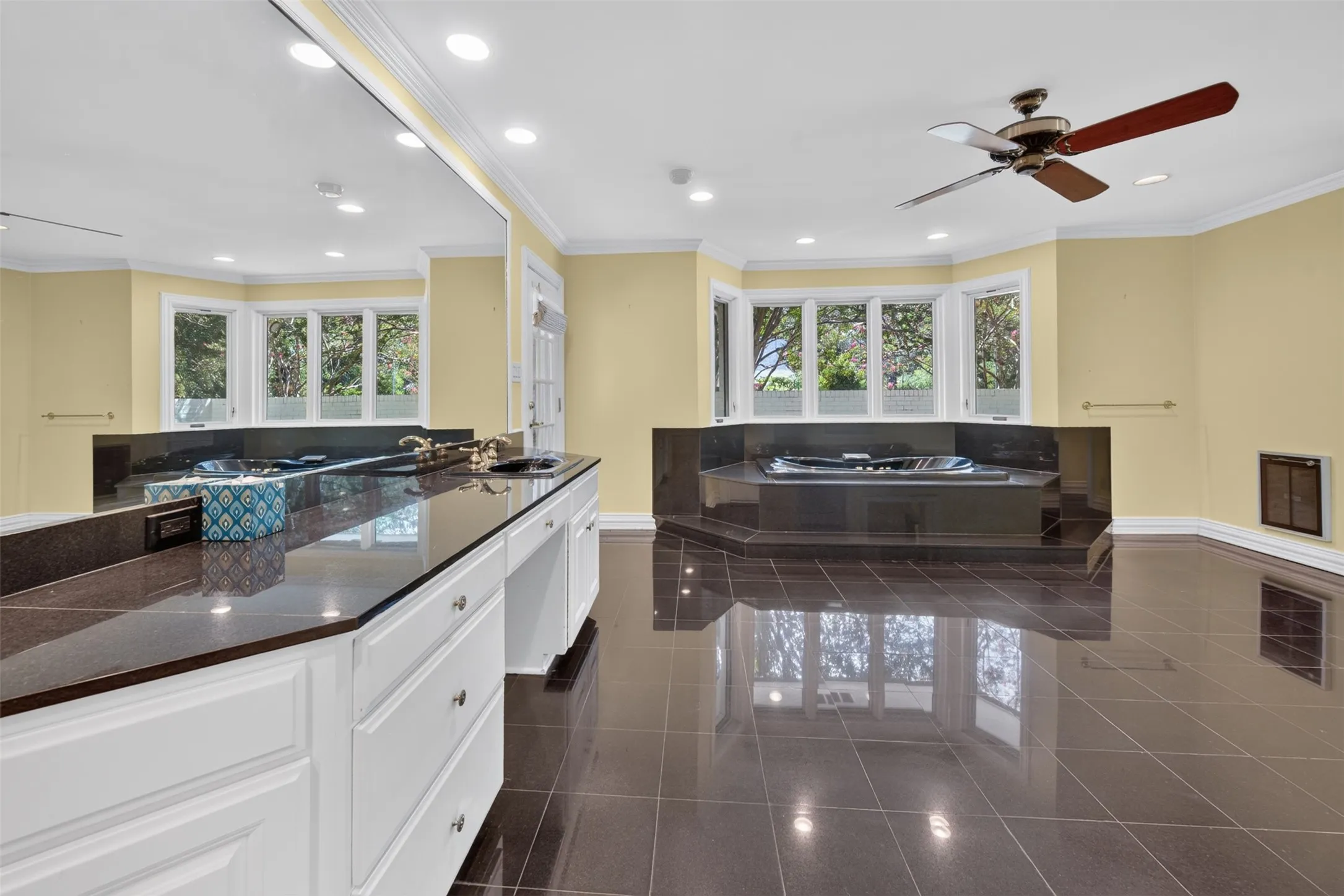 Dual vanity with
granite countertop, built-in bathtub, multiple windows, recessed lighting, and a ceiling fan