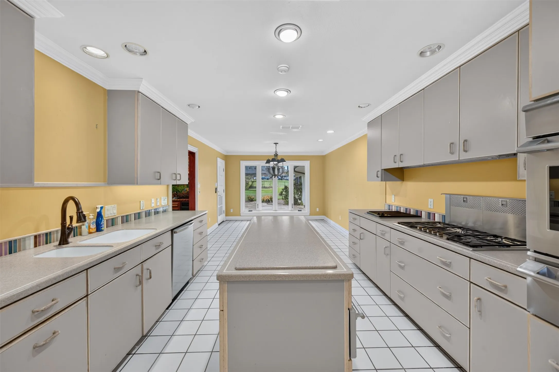 Galley kitchen featuring a gas range, built-in oven, recessed lighting, center island, and tile flooring