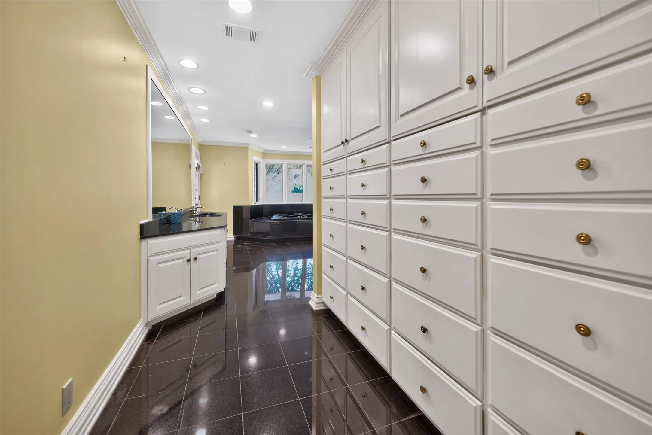 Extensive built-in cabinetry with brass hardware, tile flooring, recessed lighting, and crown molding