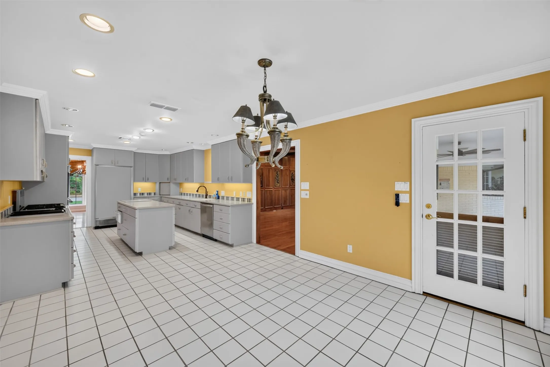 Kitchen featuring an island, recessed lighting, tile flooring, gray cabinetry, and a full-light glass panel door