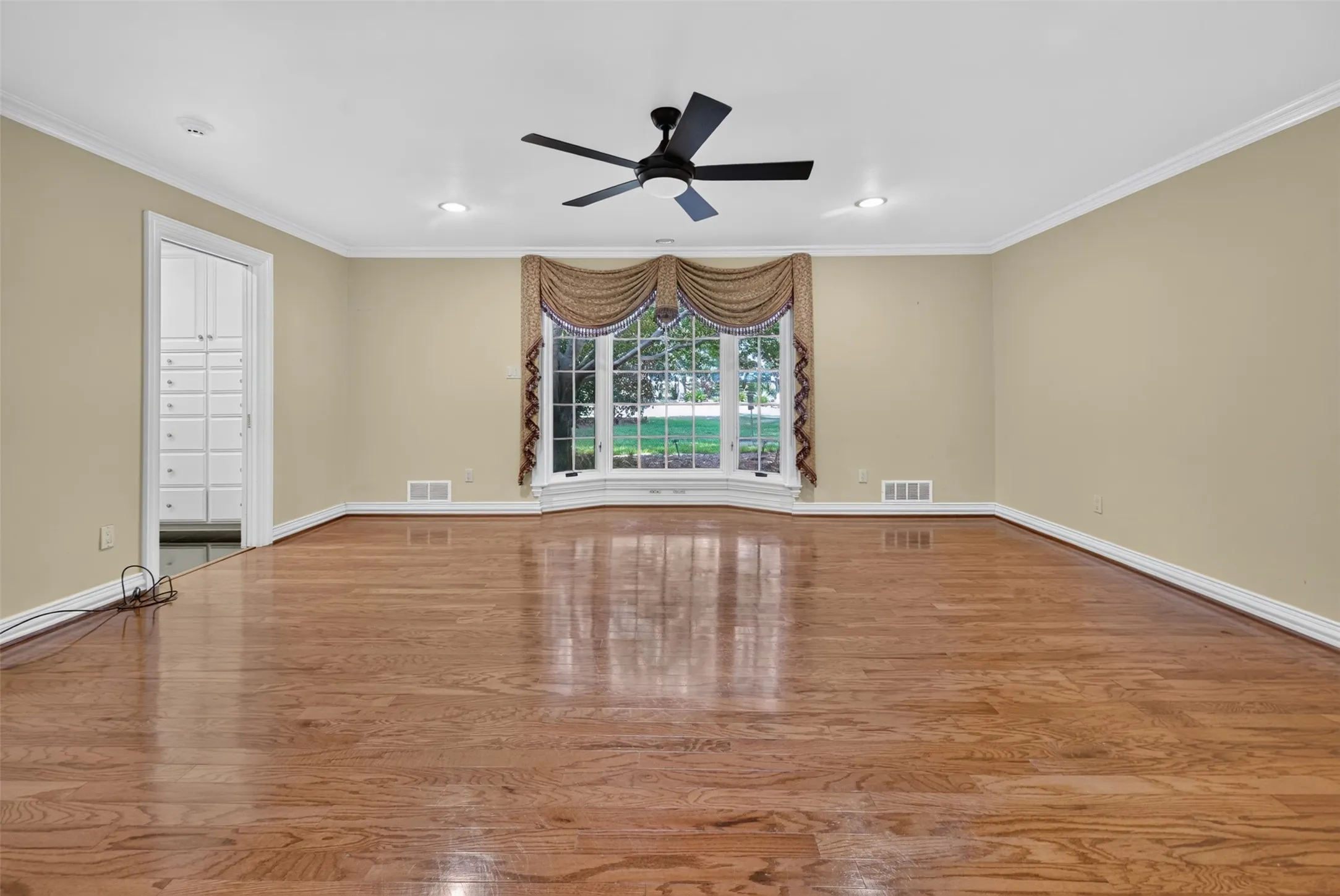 Hardwood flooring, bay window, recessed lighting, ceiling fan, and built-in cabinetry