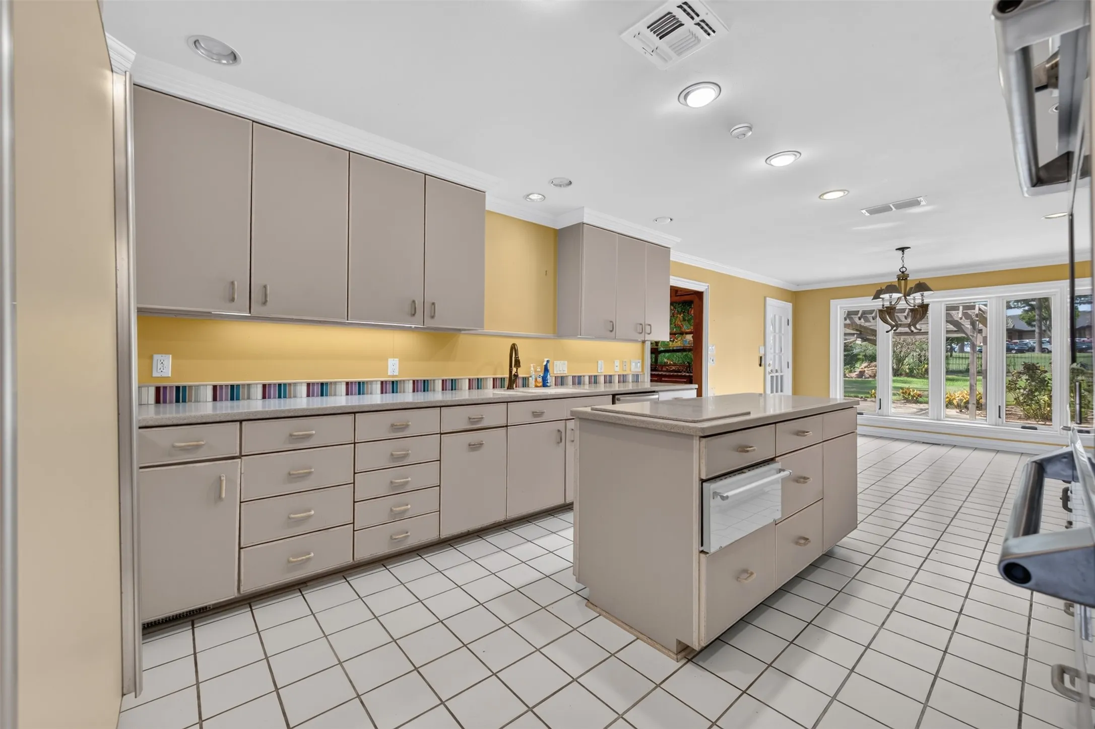 Kitchen with recessed lighting, a center island, extensive cabinetry, a tiled floor, and a large window overlooking the exterior