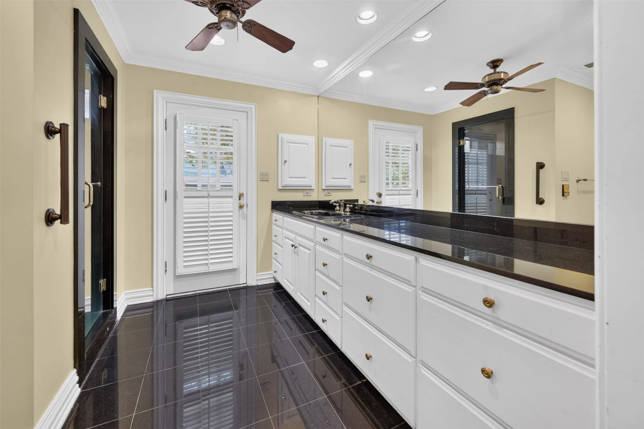 White cabinetry with gold-tone hardware, granite countertop, and granite flooring