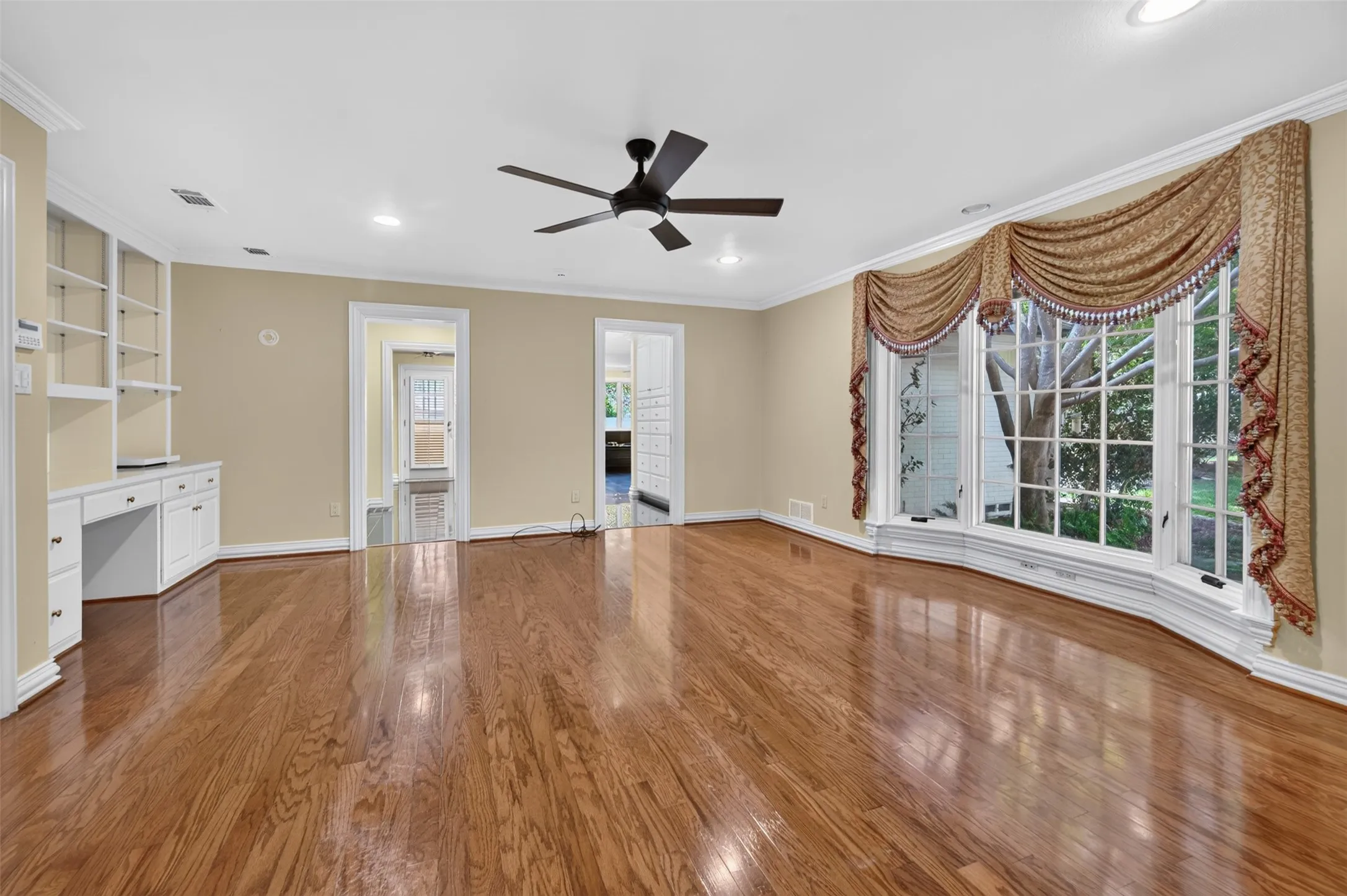 Hardwood flooring, ceiling fan, recessed lighting, built-in shelving, and large bay window
