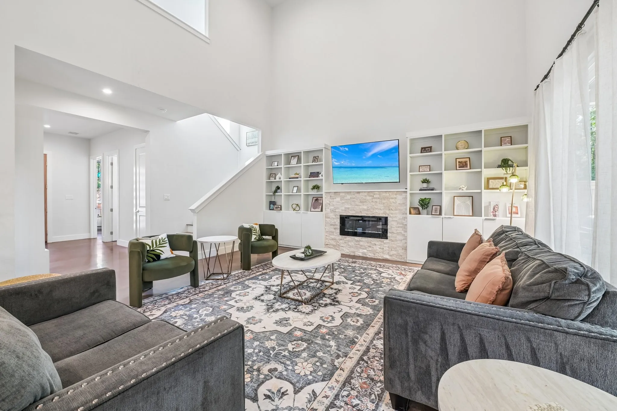 Bright, open-concept living room anchored by a gas fireplace with built-in shelving and cabinetry