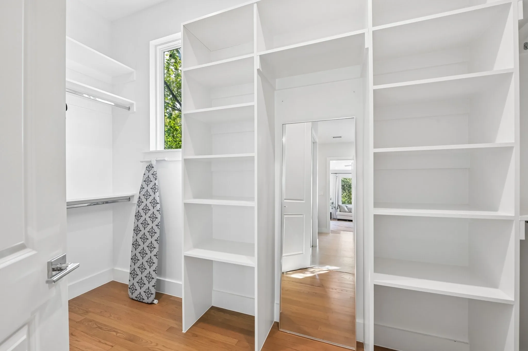 Custom shelving, wood-finish flooring, built-in mirror, chrome hardware, window for natural light