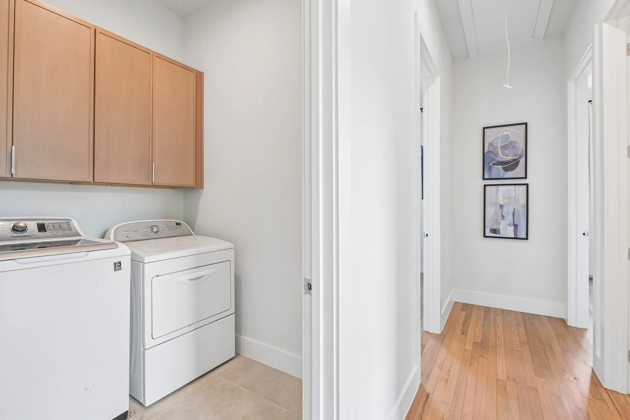 Laundry area with wood-finish upper cabinetry and tile flooring