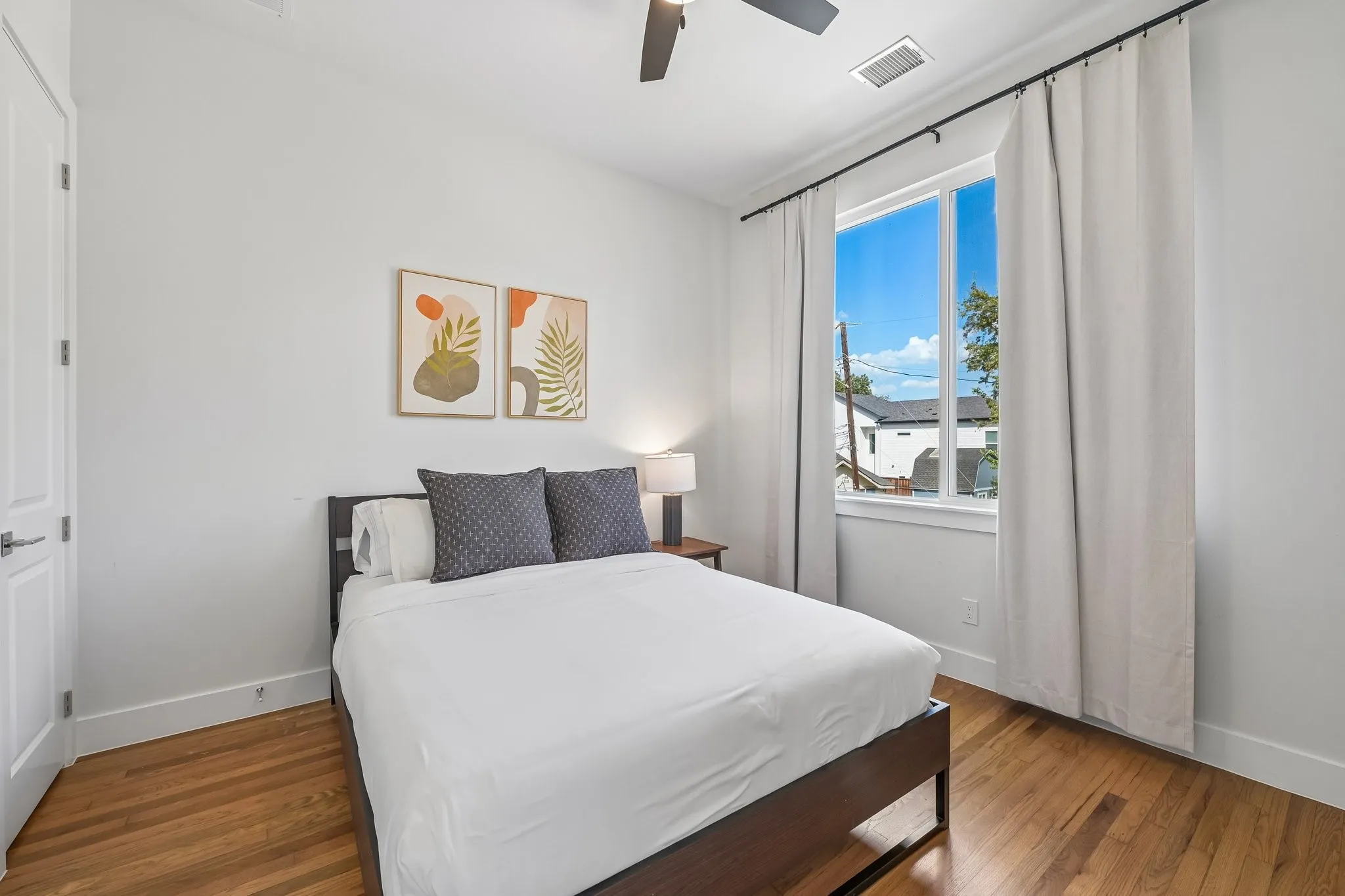 Wood-finish flooring, white walls, and a large window with white trim