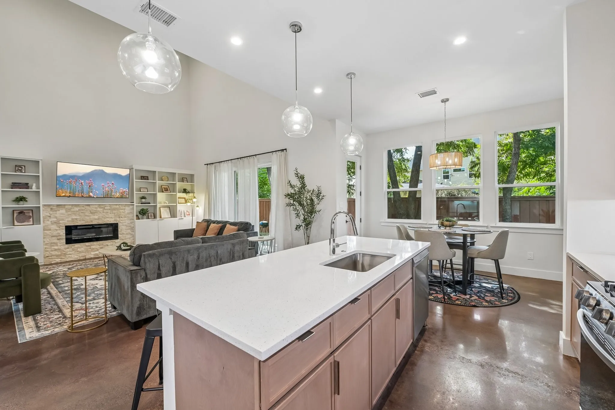 Open-concept living area featuring a vaulted ceiling, a built-in fireplace with a stacked stone surround, and an expansive kitchen island with a built-in sink