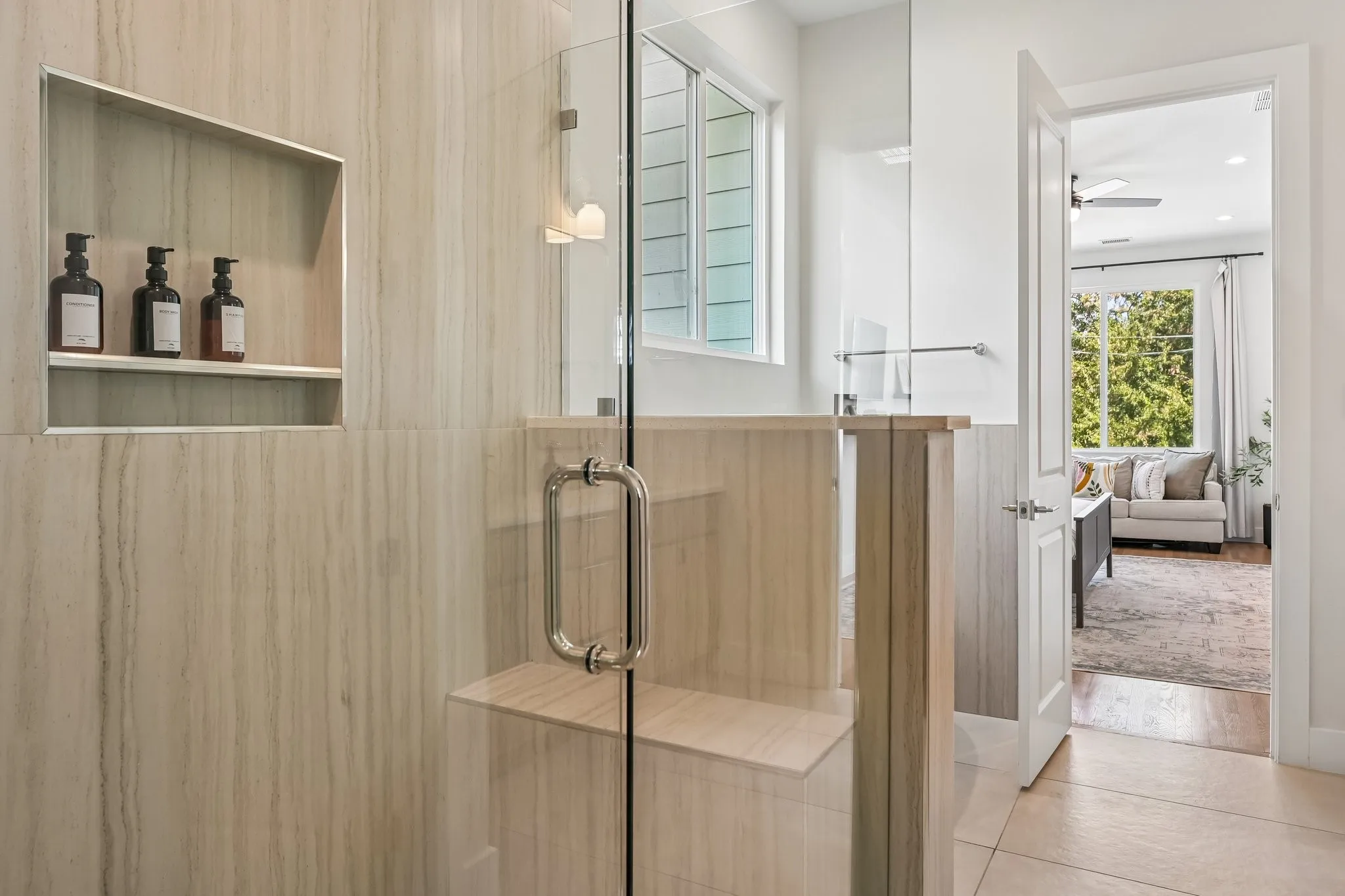 Glass-enclosed shower with a built-in bench, recessed shelf, and vertical tile surround
