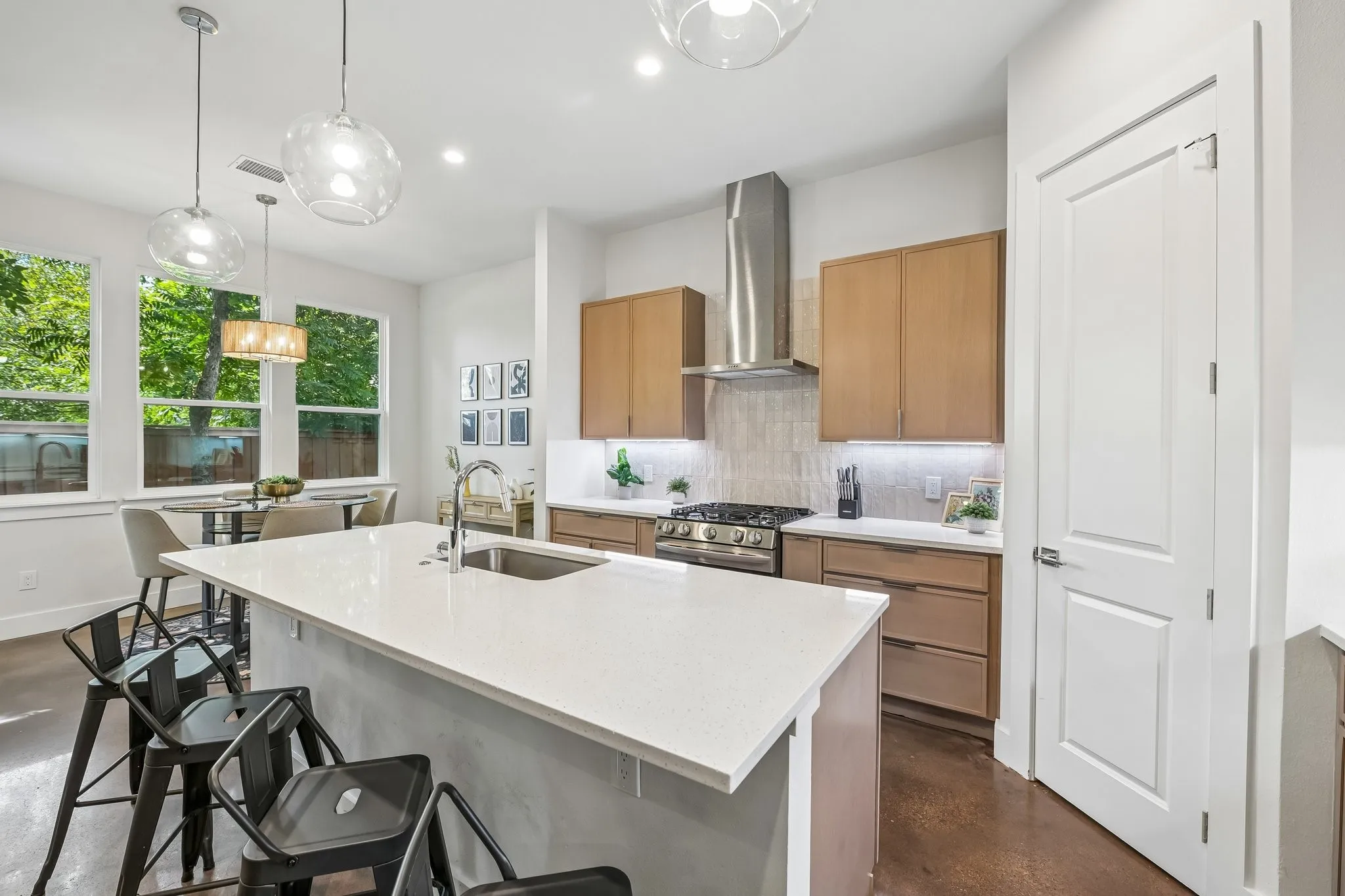 Kitchen featuring a large island with an undermount sink, stainless steel appliances, wood-finish cabinetry, and contemporary lighting fixtures