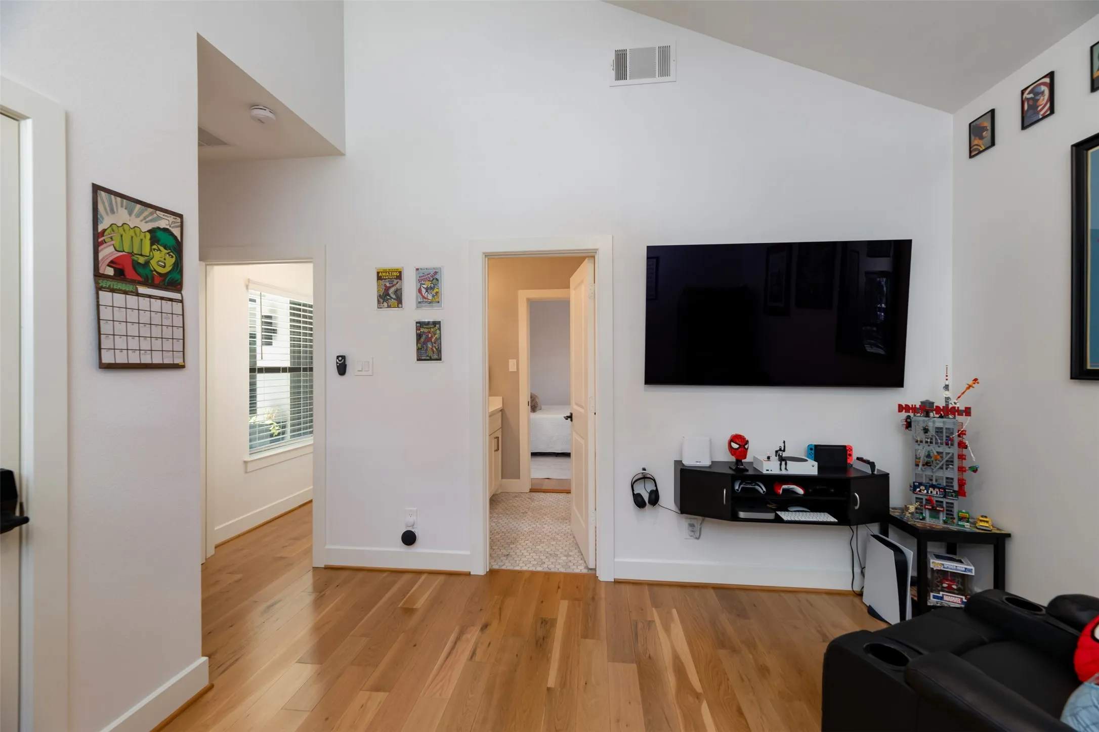 Vaulted ceiling with a ceiling fan, hardwood flooring, and white walls