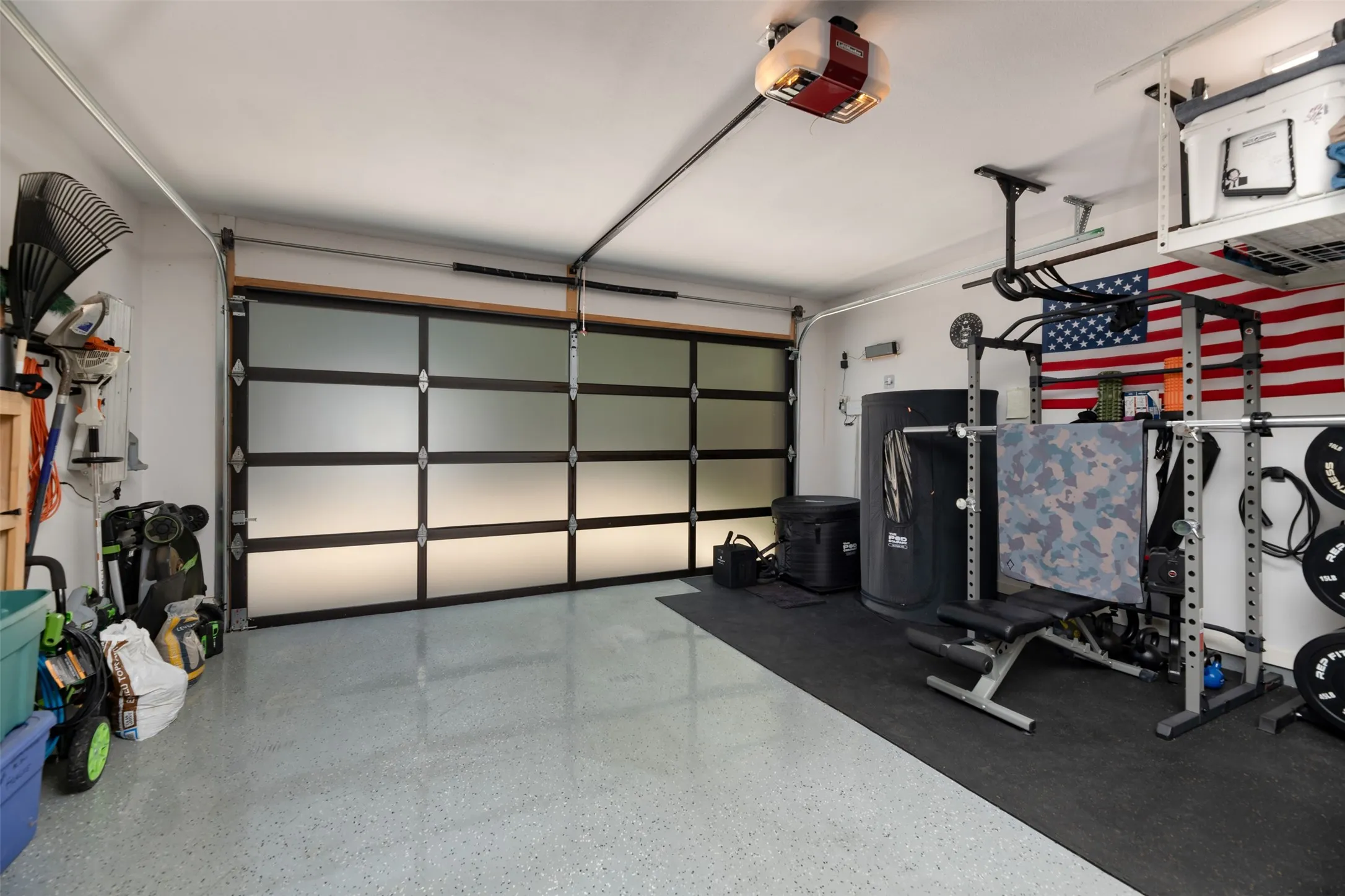Garage featuring a modern frosted glass panel door, durable epoxy flooring, and a ceiling-mounted garage door opener