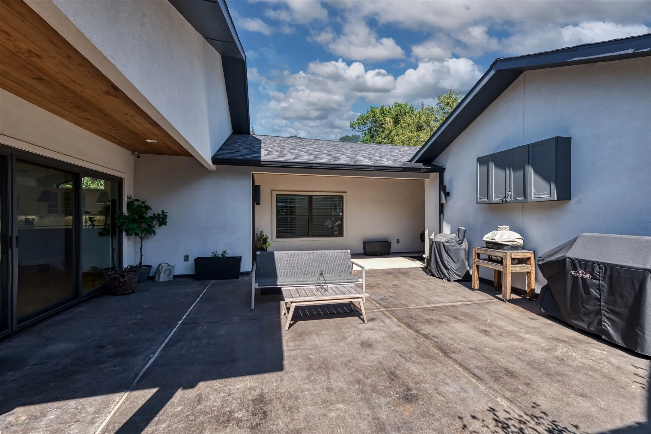 Stucco exterior with a covered patio, dark gray roof, and large sliding glass doors