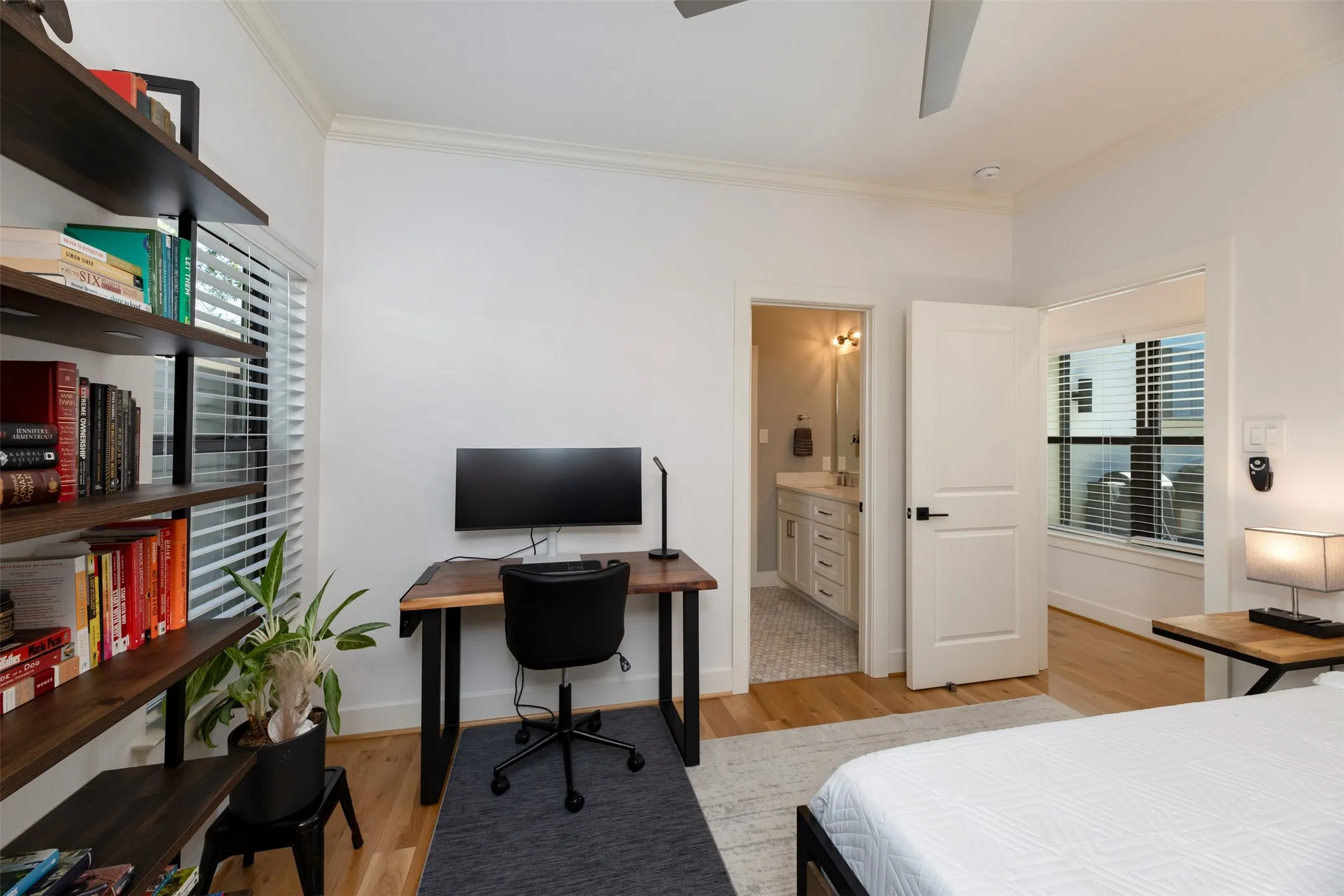 Hardwood flooring, ceiling fan, white paneled door, built-in shelving, and window with blinds