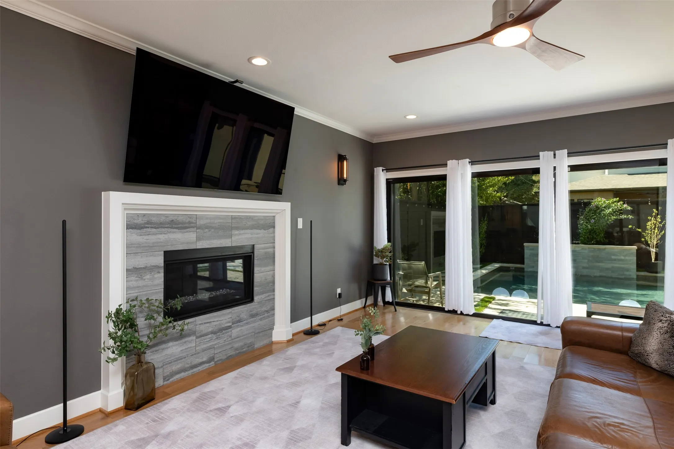 Living area featuring a modern linear fireplace with stone tile surround, recessed lighting, and wood-finish flooring