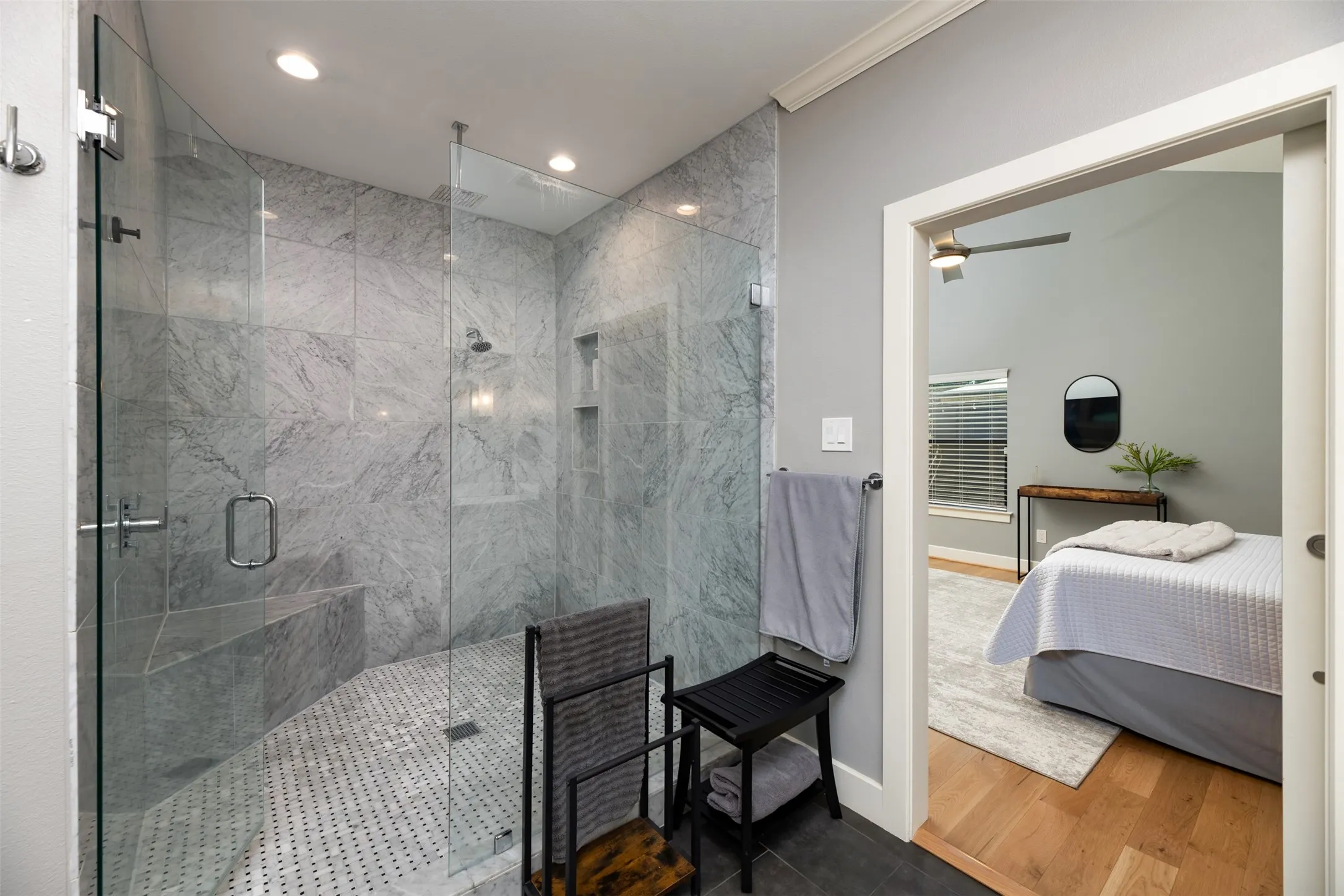 Glass-enclosed shower with a tiled bench, recessed niches, and a textured floor